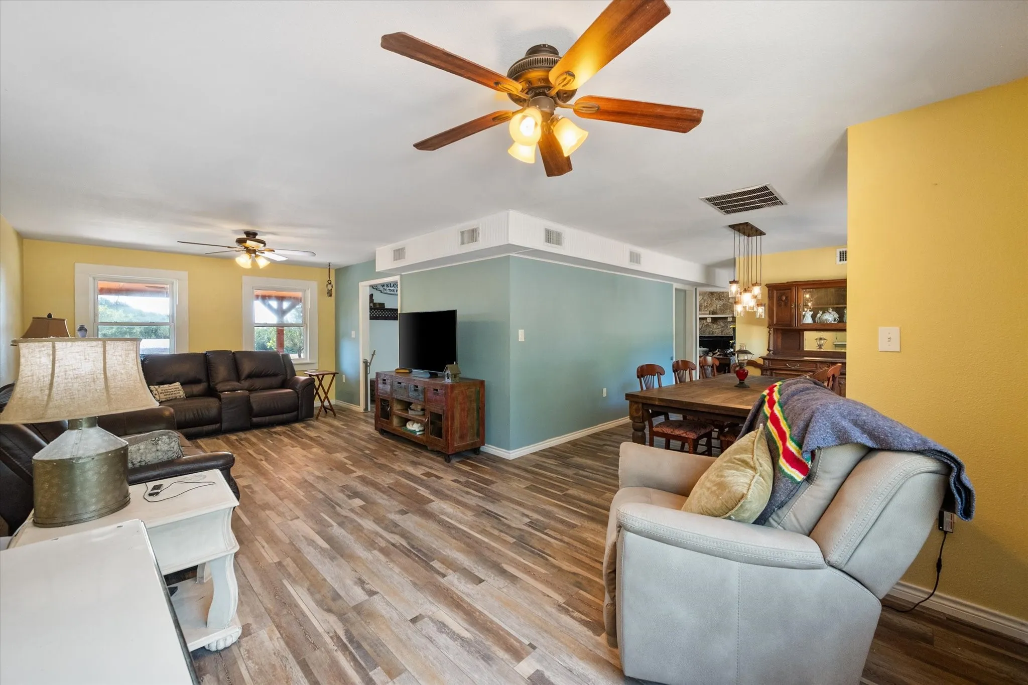 Wood-finish flooring throughout, multiple ceiling fans with light kits, and recessed lighting