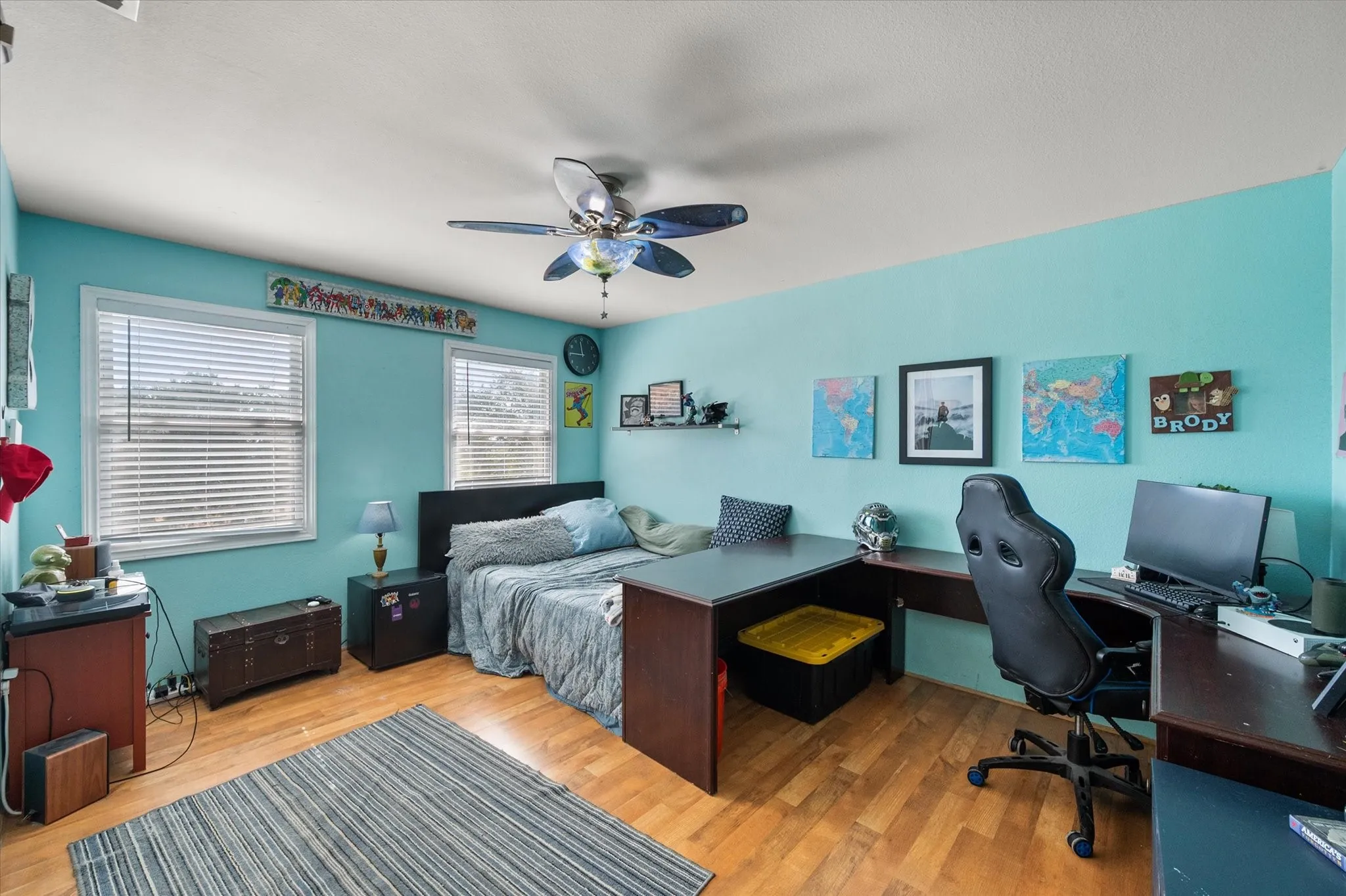 Room featuring wood-finish flooring, two windows, and a ceiling fan