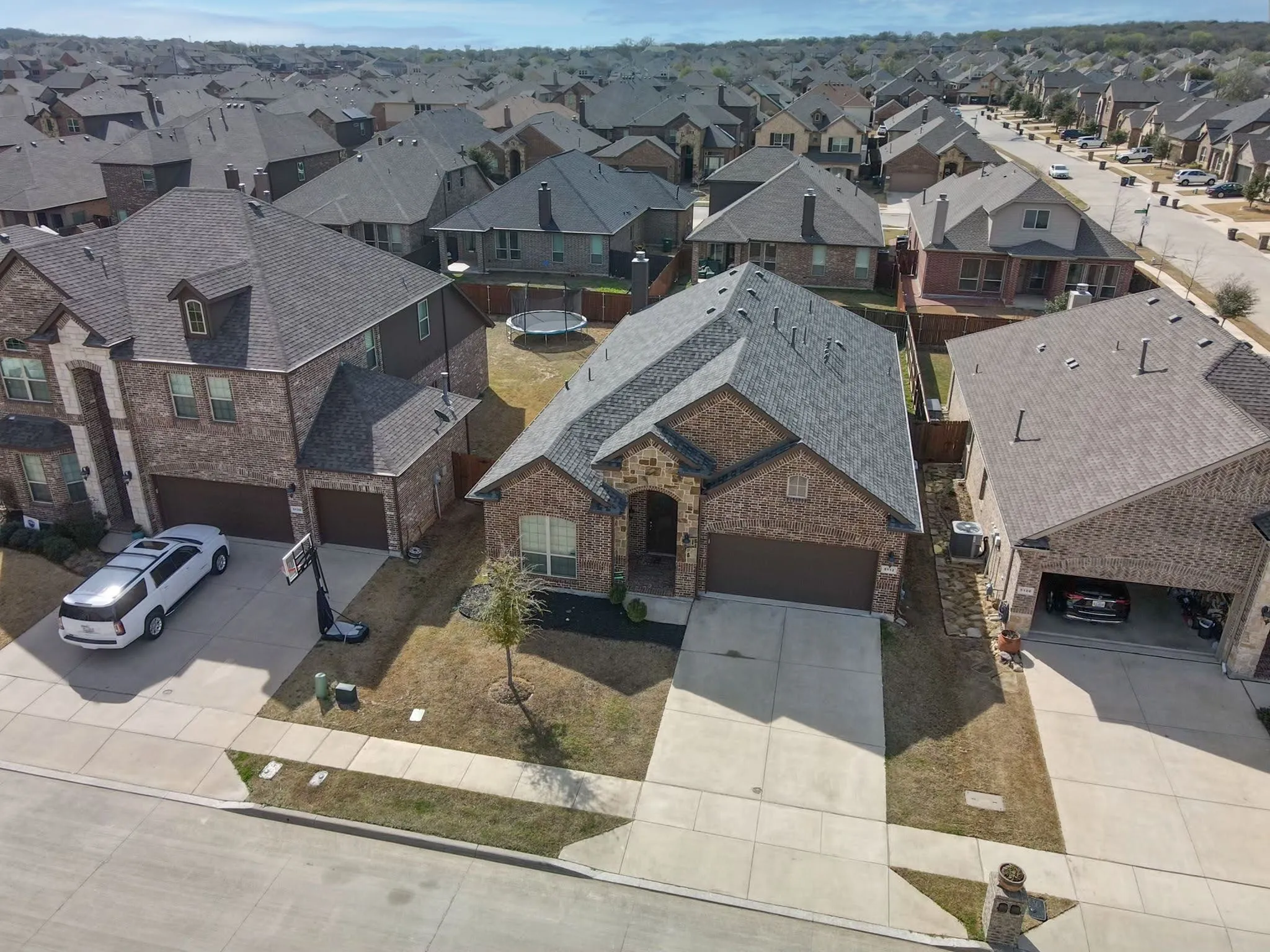 Brick facade residence featuring an attached garage, a paved driveway, and a shingled roof