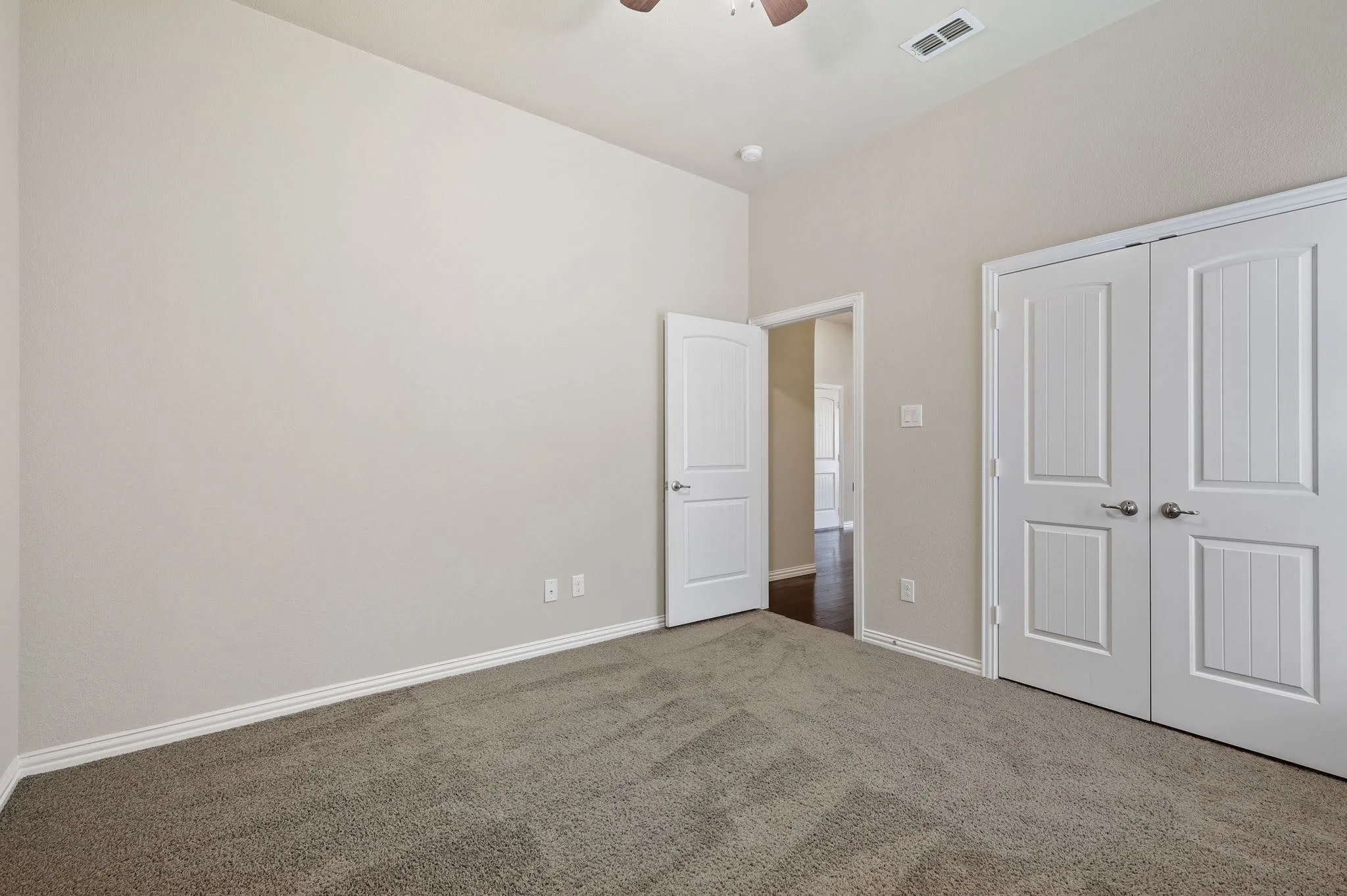 Neutral color palette with textured carpeting, white baseboards, and a ceiling fan