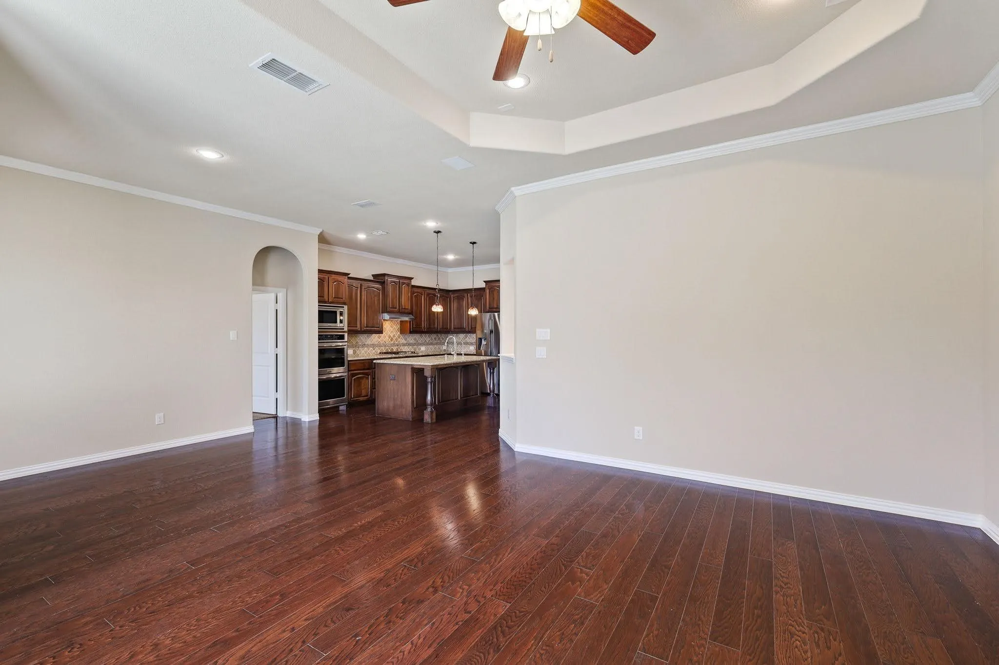Wood-finish flooring with recessed lighting, crown molding, and a tray ceiling