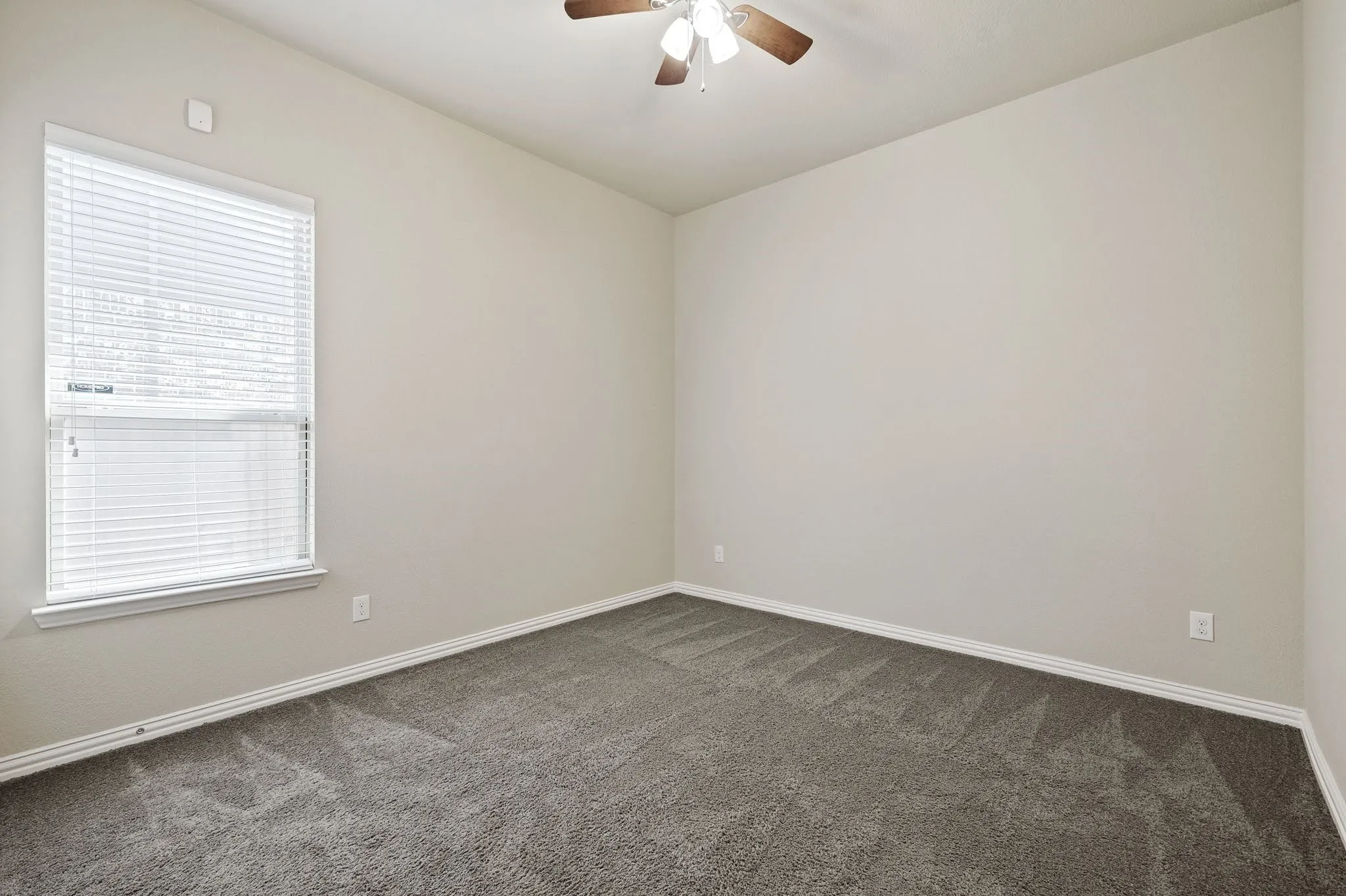 Neutral-toned walls, gray carpeting, and a ceiling fan with light fixture