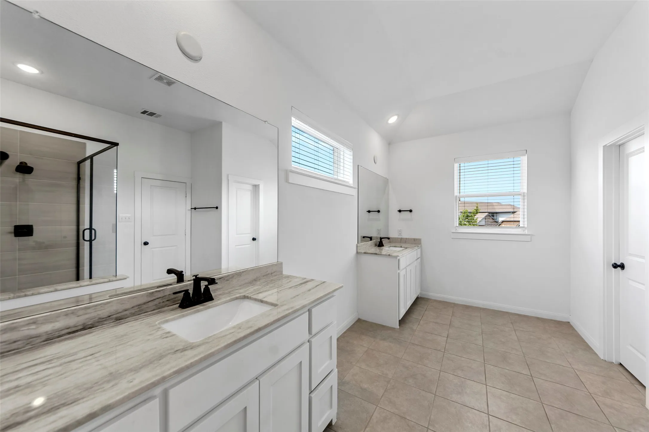 Dual vanities with undermount sinks, stone countertops, and matte black fixtures