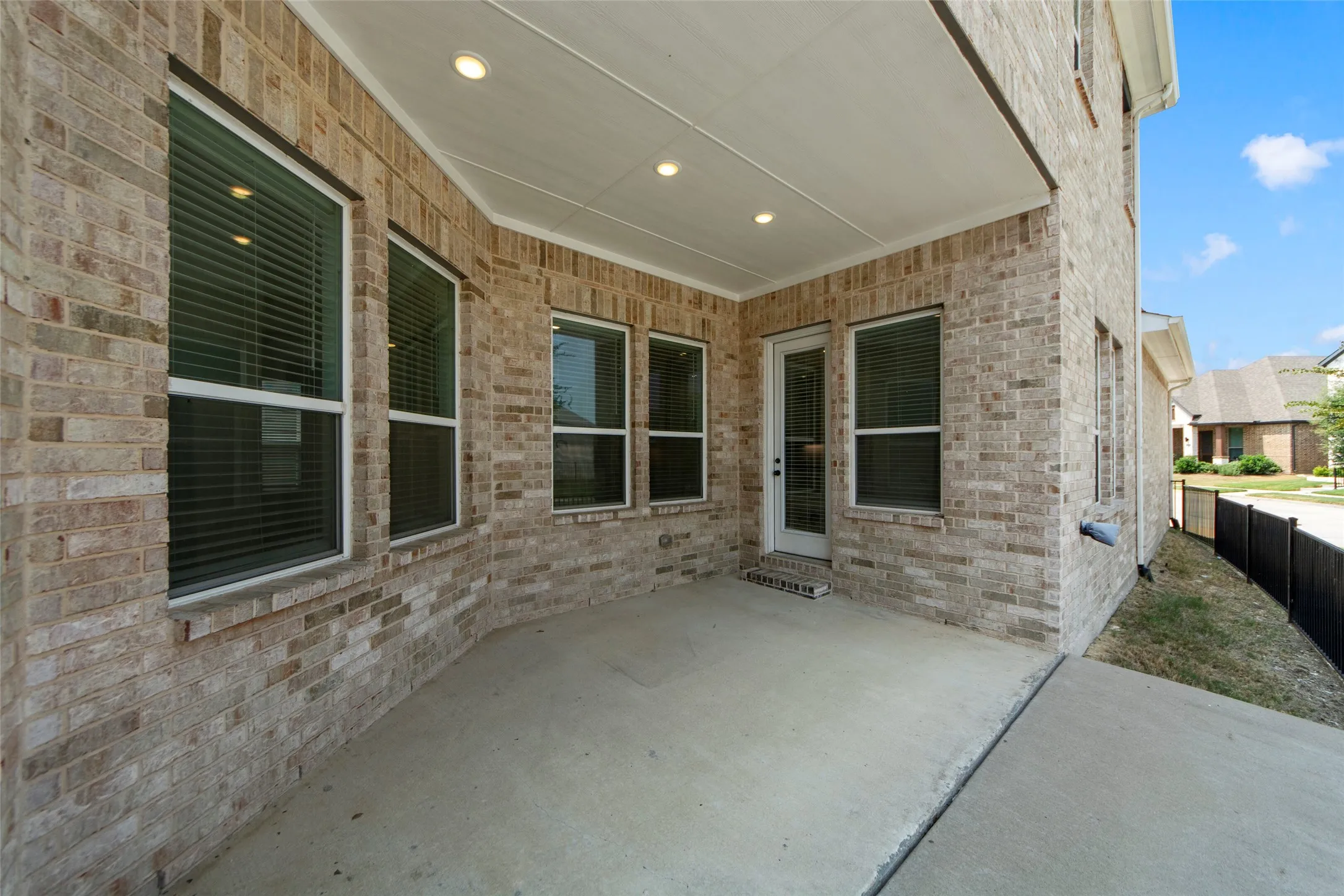 Covered patio featuring recessed lighting, a concrete surface, and brick exterior walls