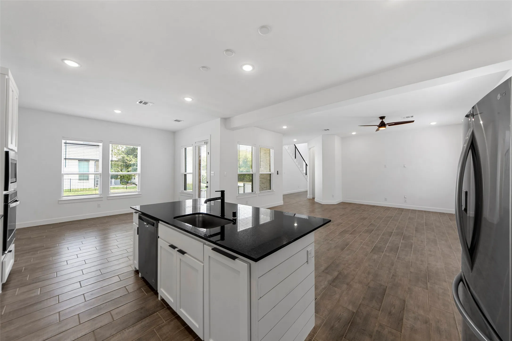 Kitchen island with black countertop, integrated sink, and dishwasher