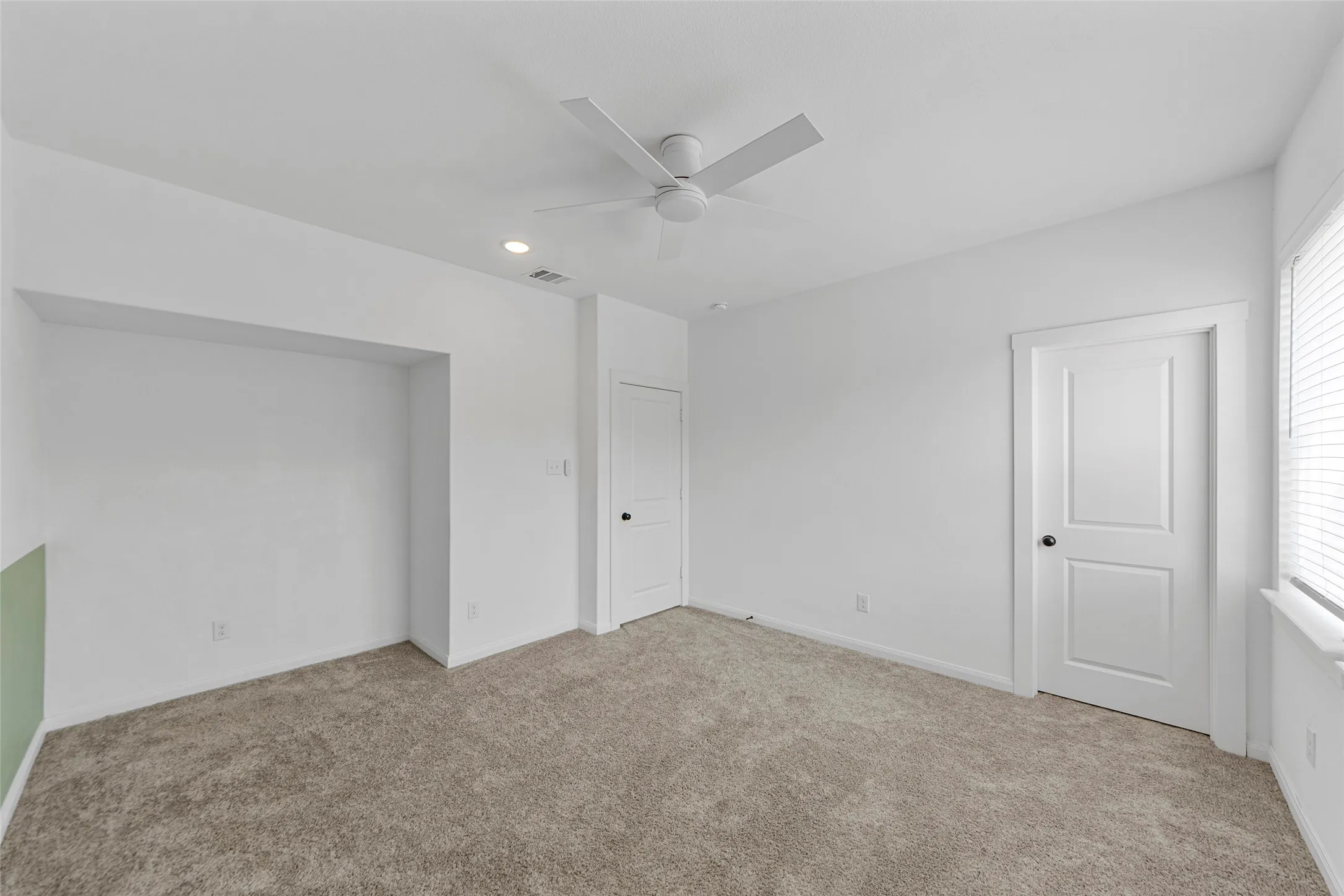 Plush carpet flooring, recessed lighting, ceiling fan, white interior doors, and a built-in wall niche