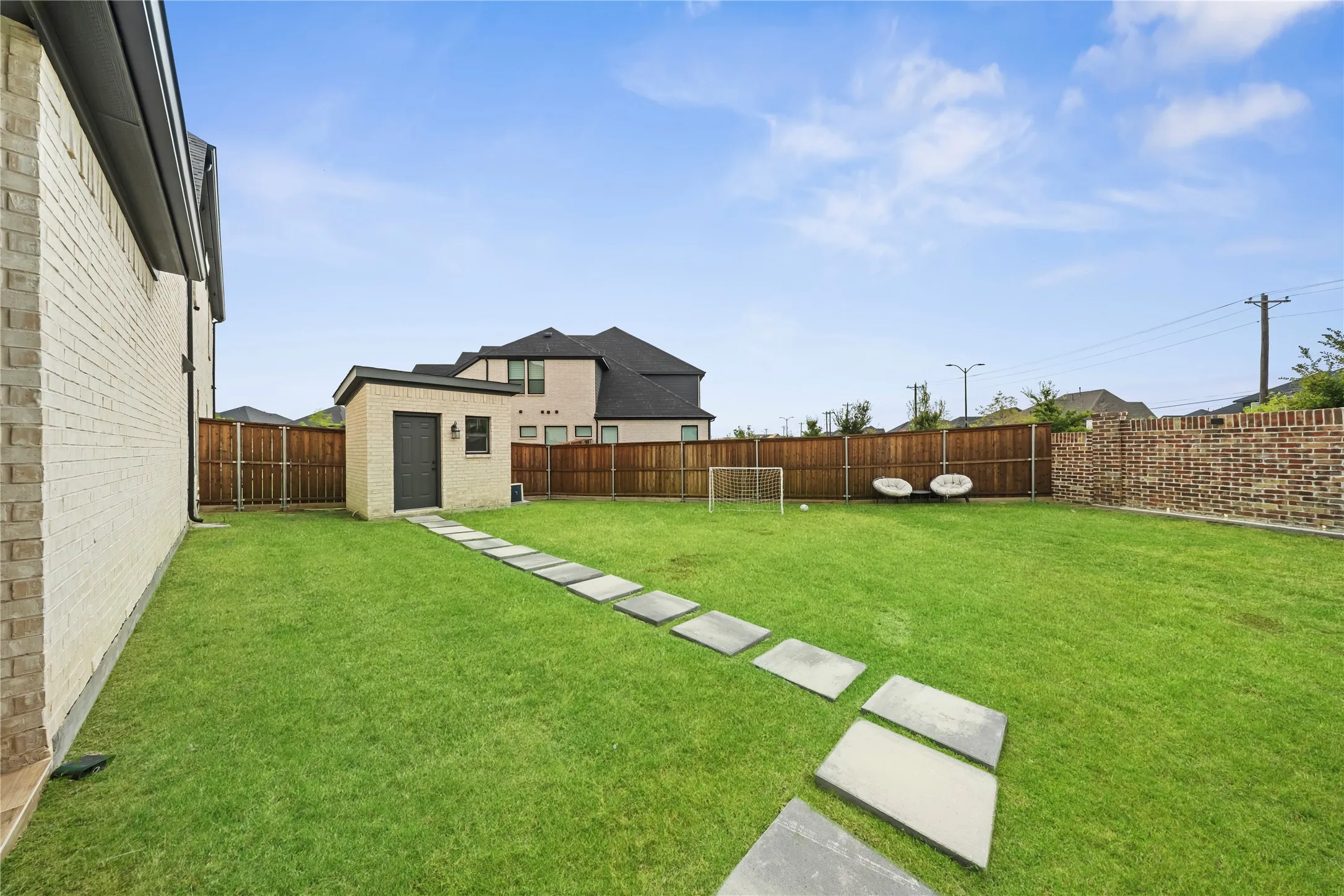 Expansive backyard featuring a manicured lawn, wood fencing, and a detached shed with a sloped roof