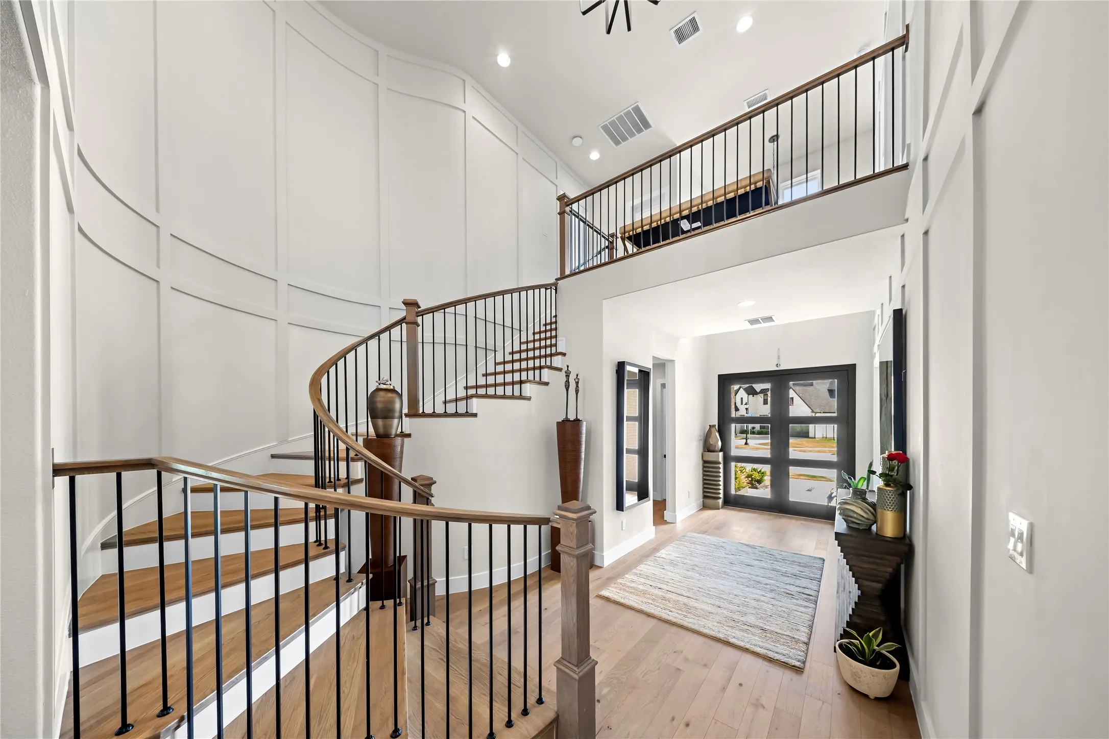 Grand foyer featuring a spiral staircase with wood treads, black metal balusters, and a wood handrail