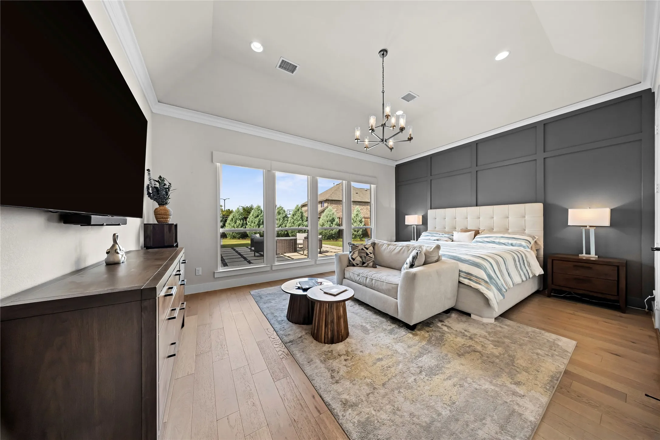 Vaulted ceiling with recessed lighting, wood-finish flooring, a wall of windows, dark paneled accent wall, and a contemporary chandelier