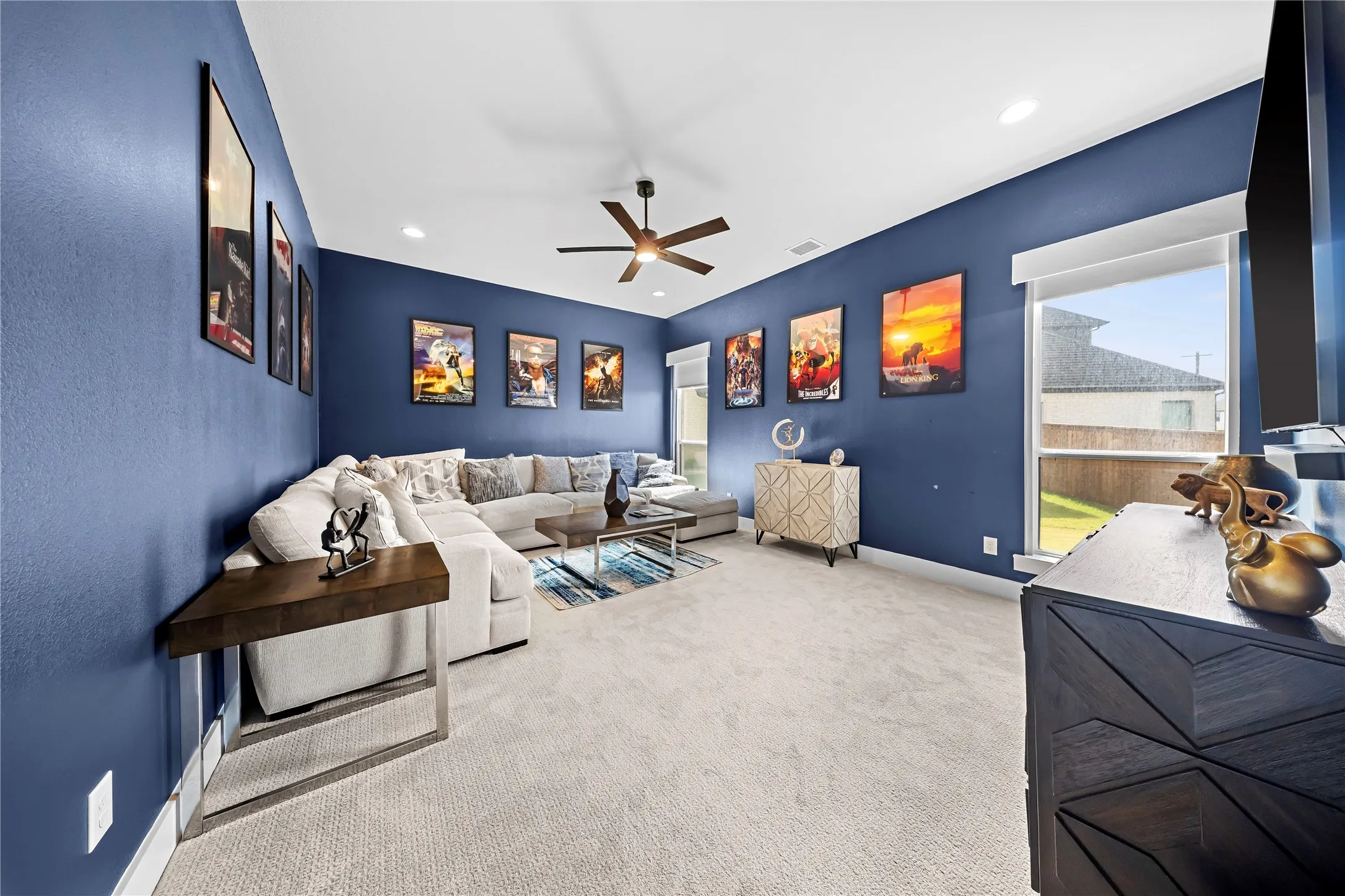Recessed ceiling lights, ceiling fan, multiple windows with roller shades, and carpeted flooring