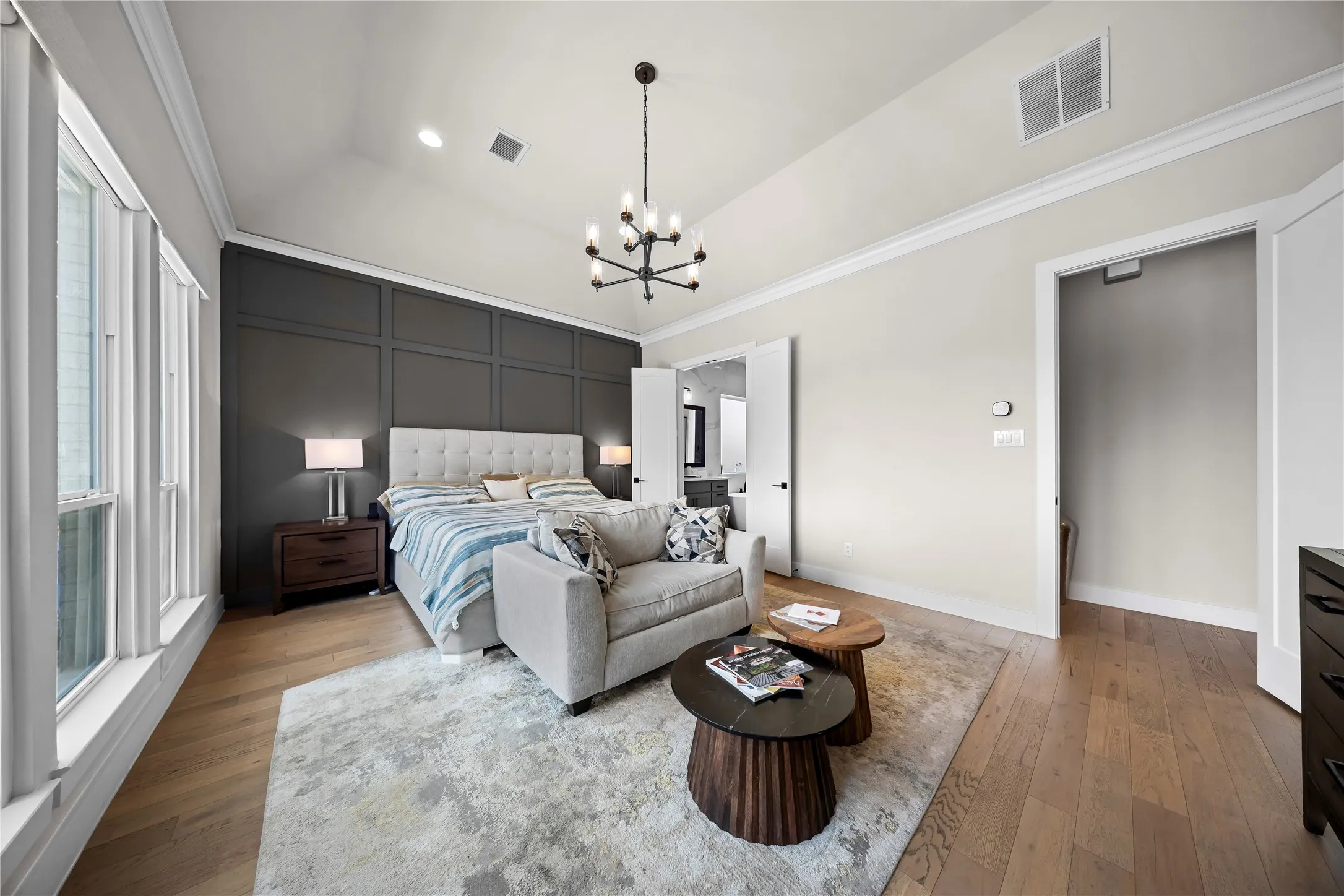Vaulted ceiling featuring a contemporary chandelier, wood-finish flooring, and a paneled accent wall