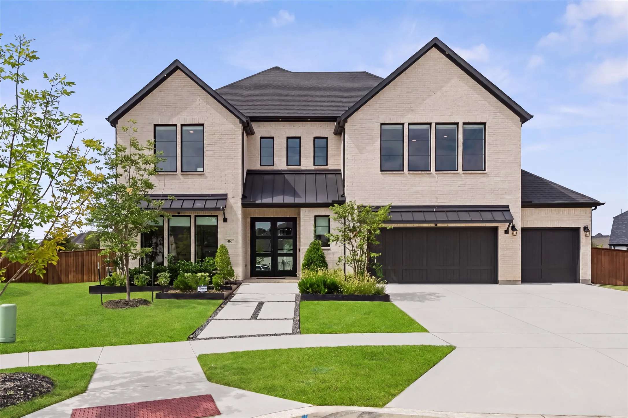 Brick exterior with dark-framed windows, a black asphalt shingle roof, and a three-car garage