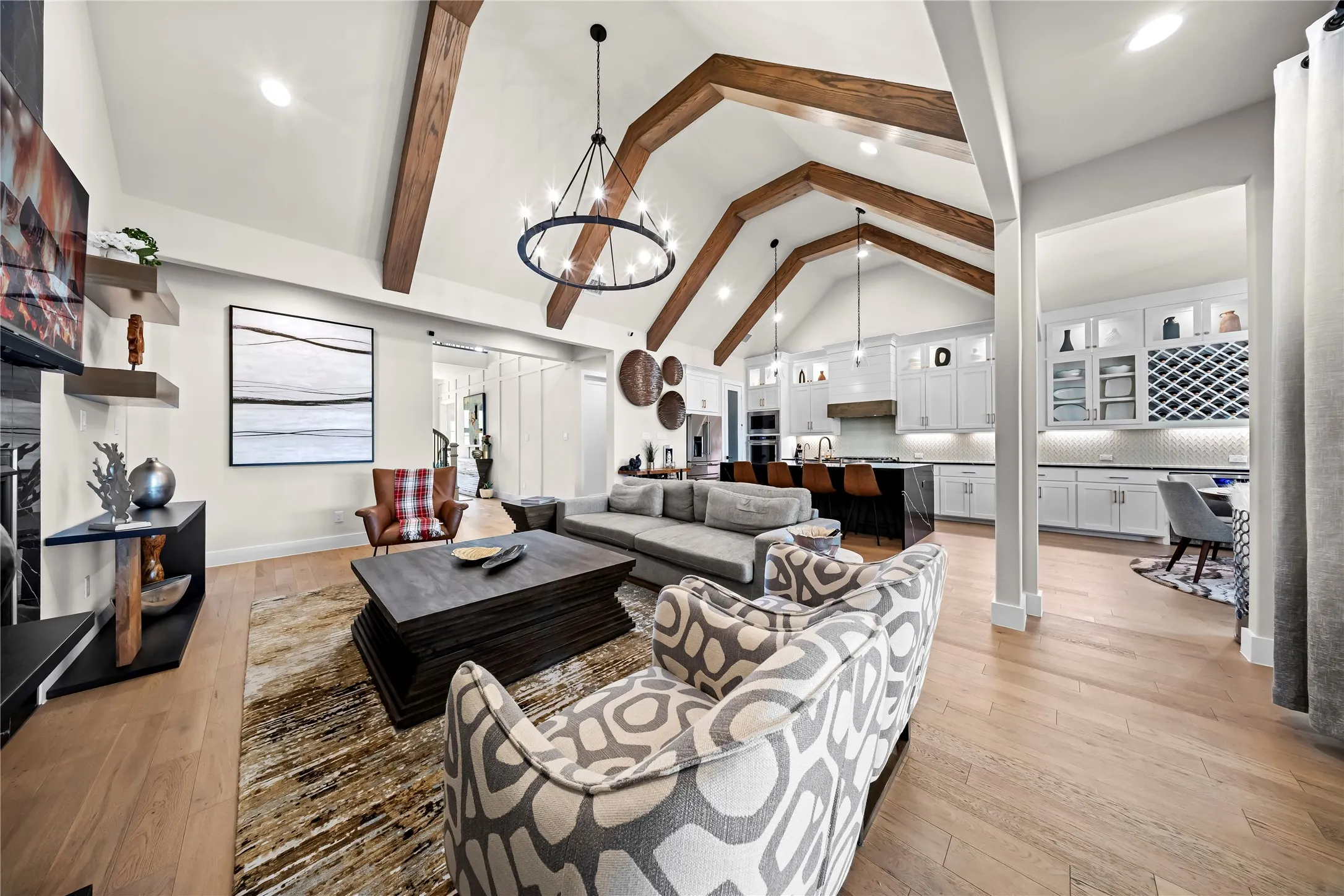 Vaulted ceiling with exposed wood beams, central chandelier, and wood-finish flooring