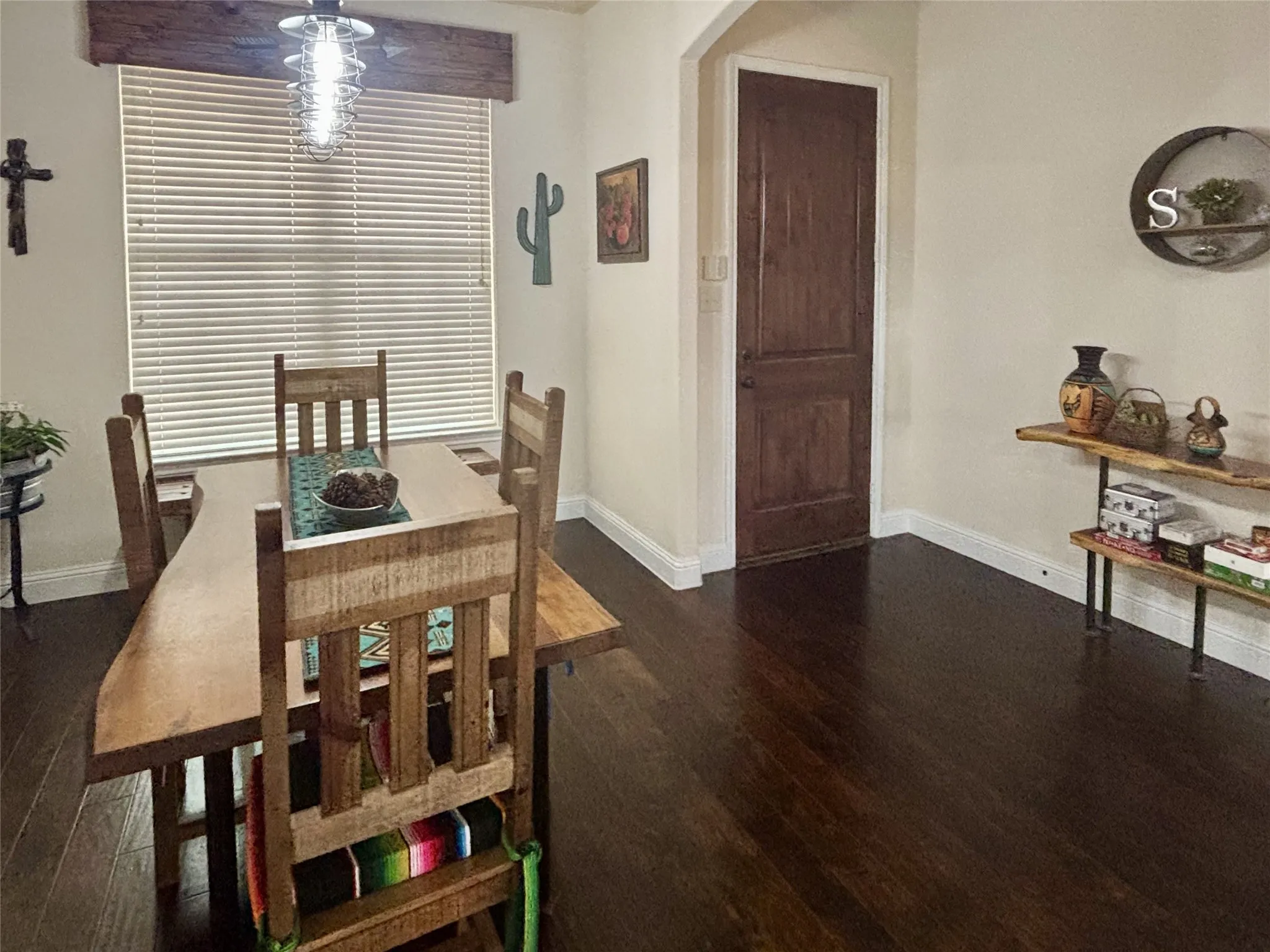 Dark wood-finish flooring, wood door, and white baseboards