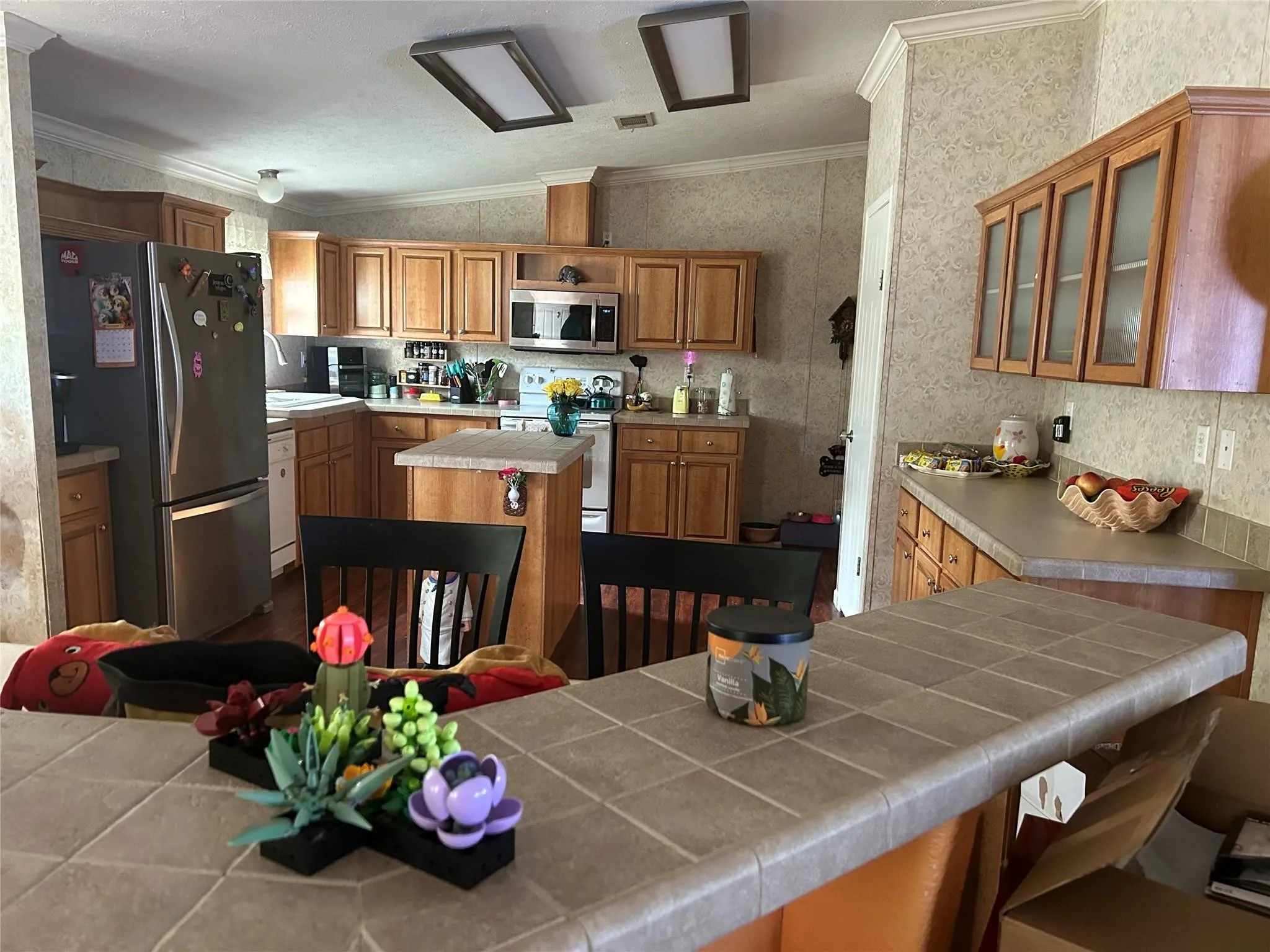 Kitchen featuring wood cabinetry, stainless steel appliances, a tiled countertop, and a built-in breakfast bar