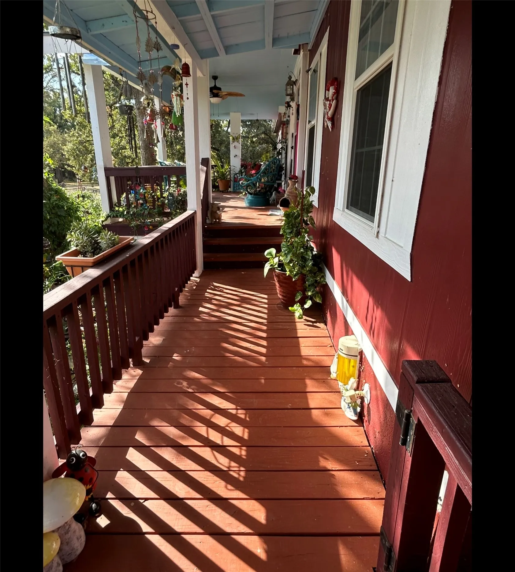 Wraparound porch with wood-finish decking, white columns, and a light blue ceiling