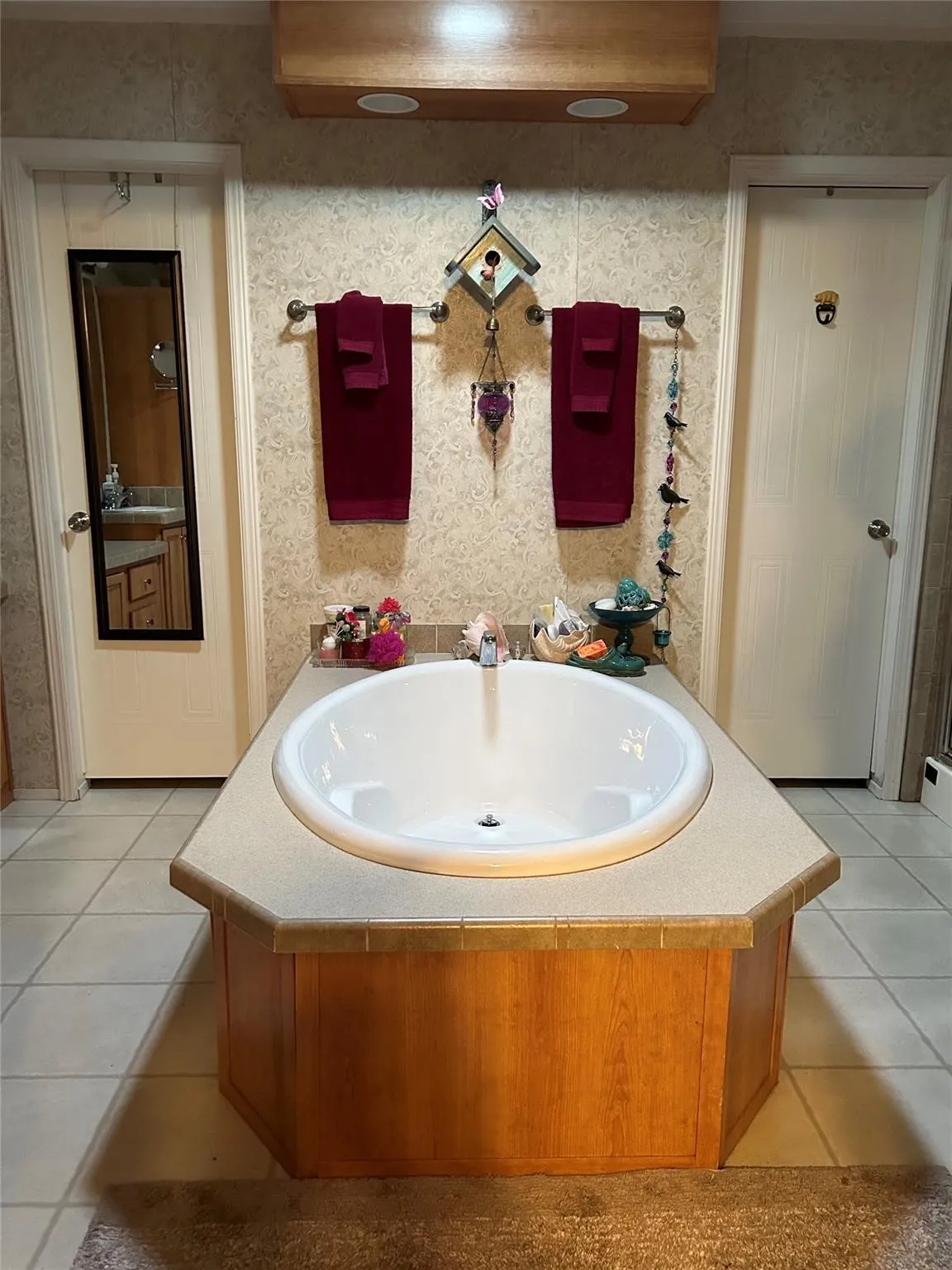 Built-in soaking tub with a tiled surround and wood-finish paneling, complemented by neutral tile flooring