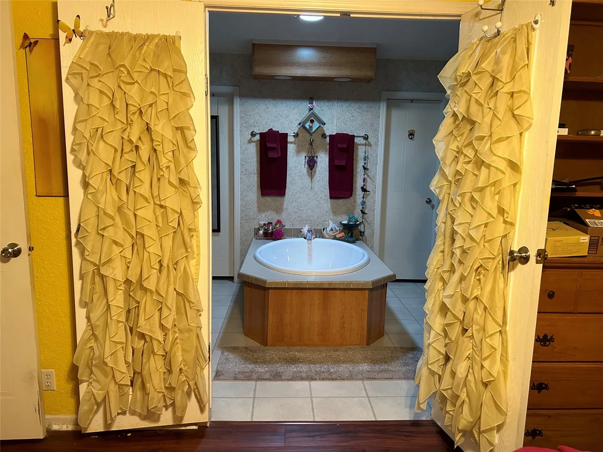 Built-in drop-in bathtub with a wood-finish surround, tile flooring, and a wall-mounted towel bar