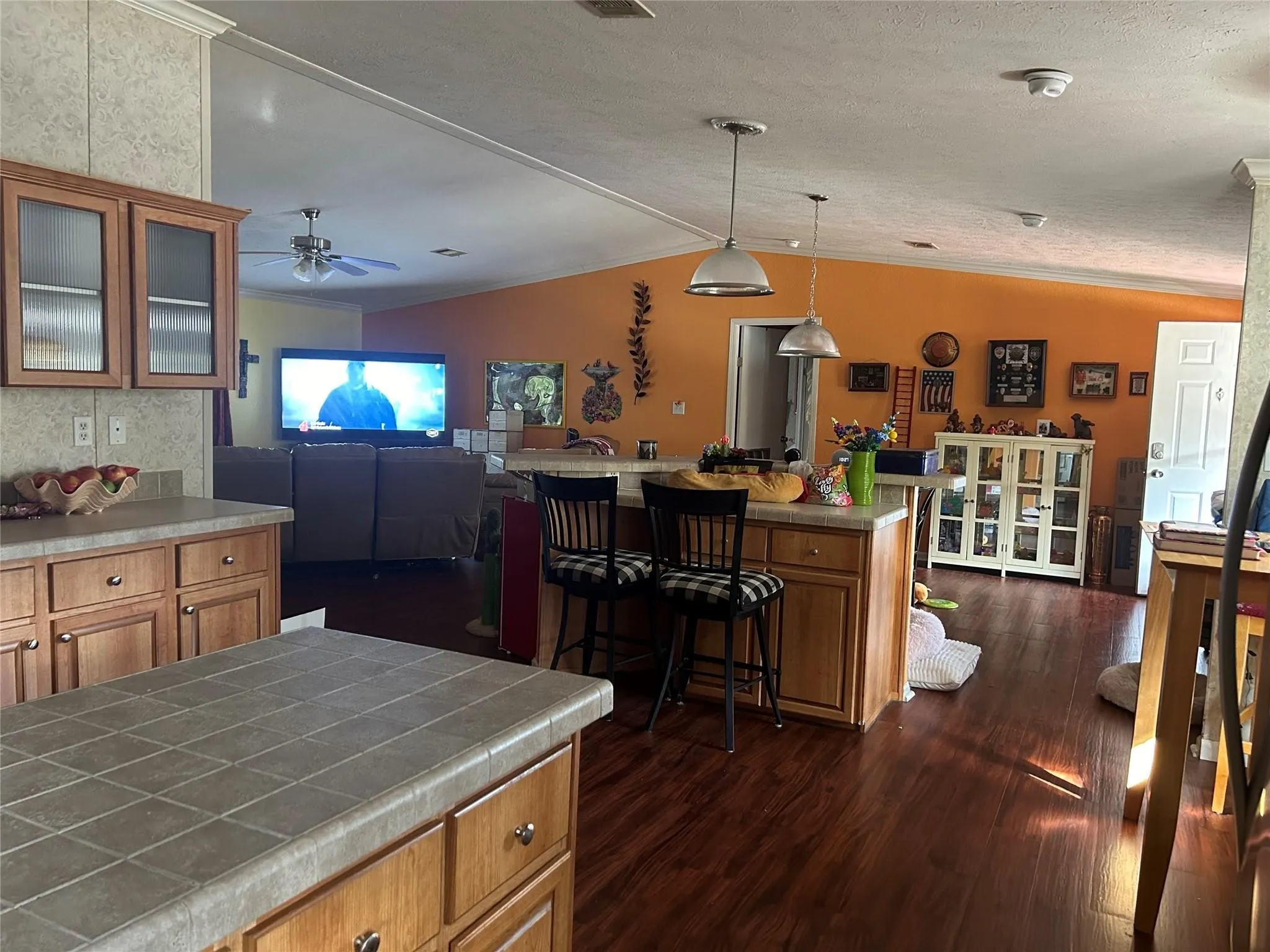Wood-finish flooring throughout, with a kitchen island featuring a tile countertop