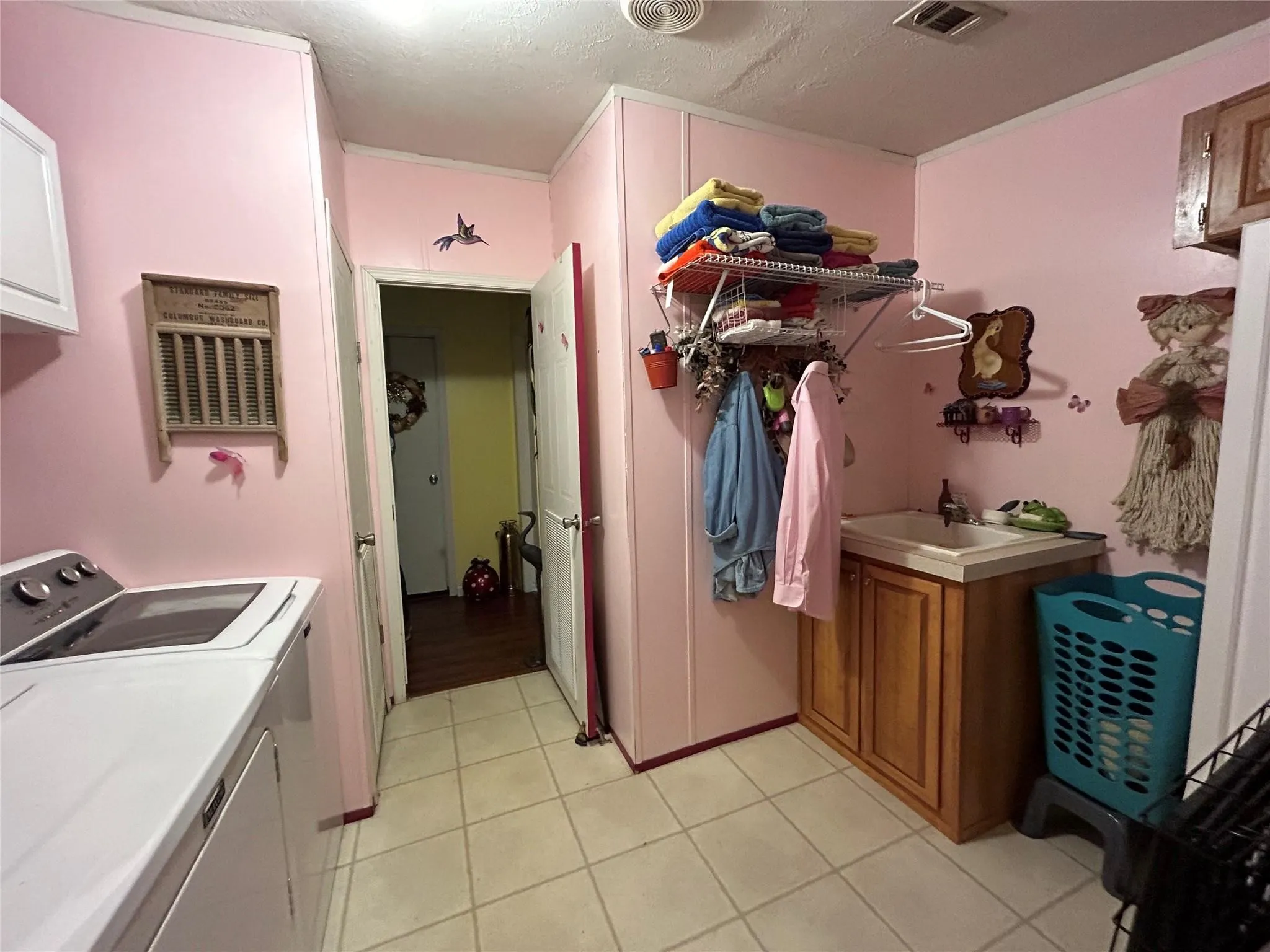 Tile flooring, built-in cabinetry, wall-mounted shelving, utility sink, and overhead lighting