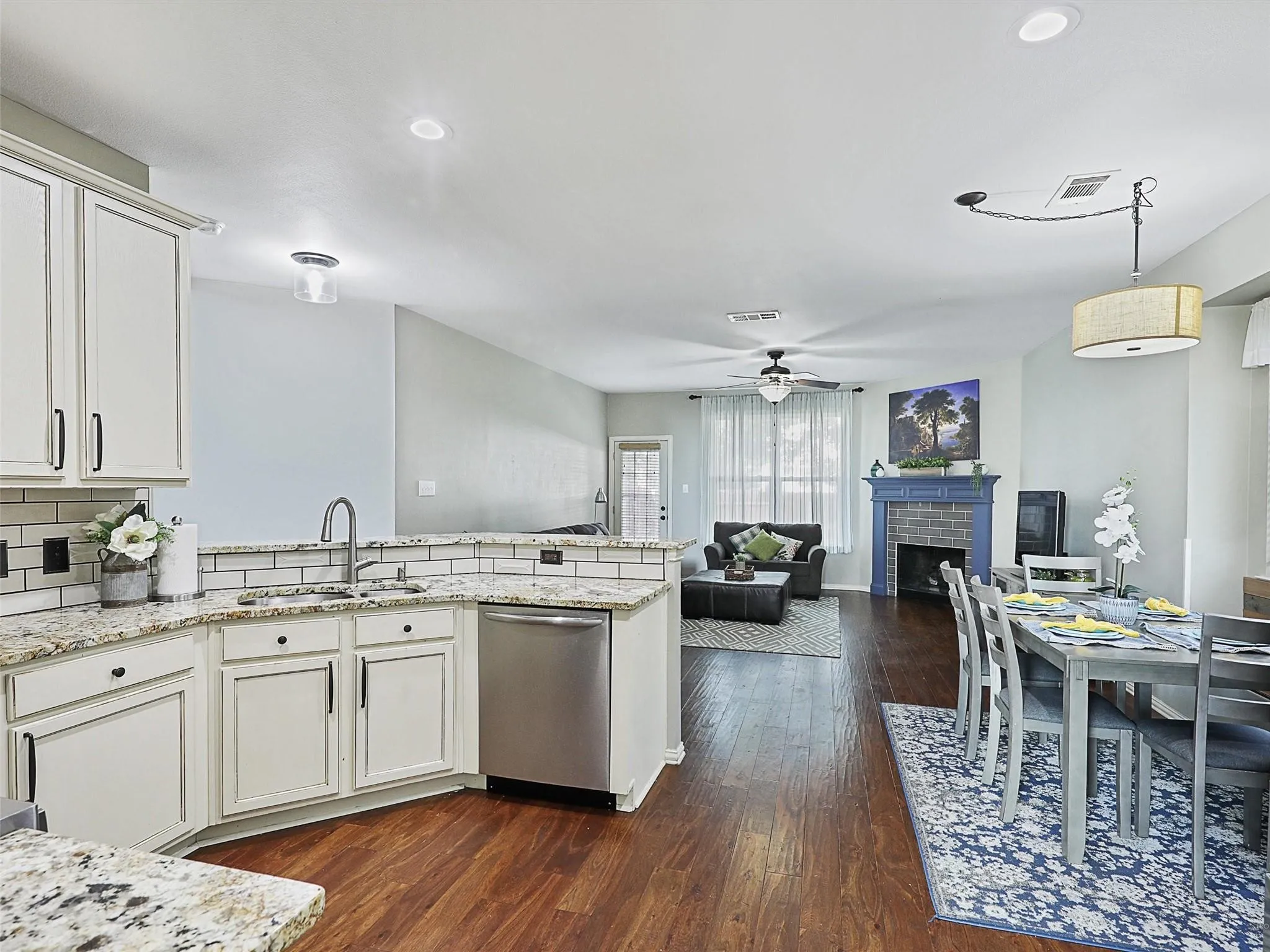 Kitchen featuring white cabinetry with dark hardware, a stainless steel dishwasher, and granite countertops