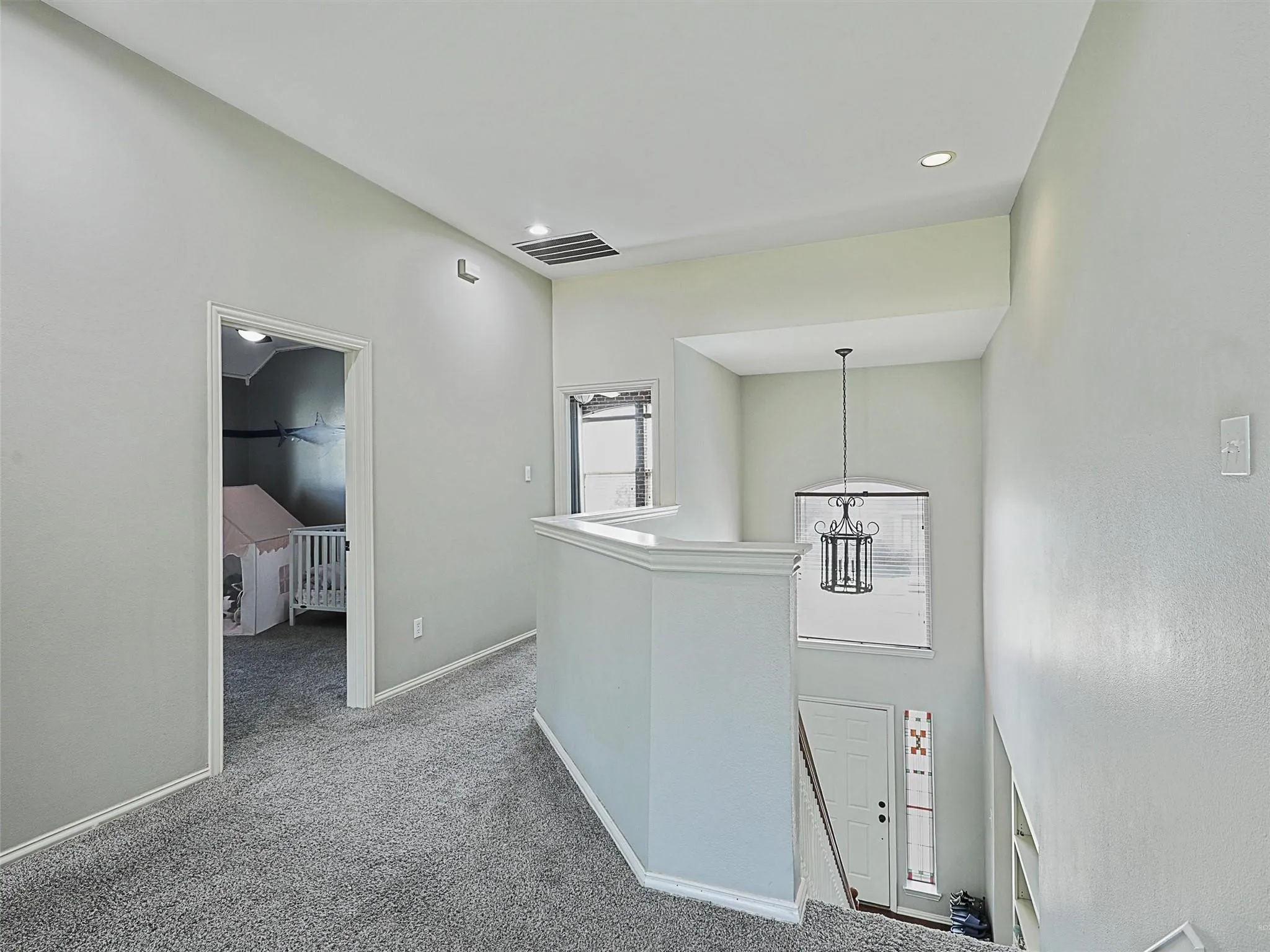 Modern hallway featuring crisp white cabinetry with integrated storage, recessed ceiling lighting, and neutral carpet flooring
