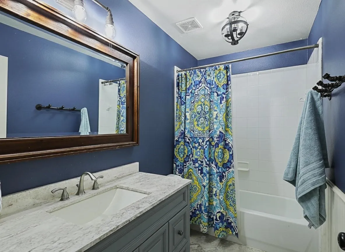 Vanity with an undermount sink, a stone countertop, and a wood-framed mirror