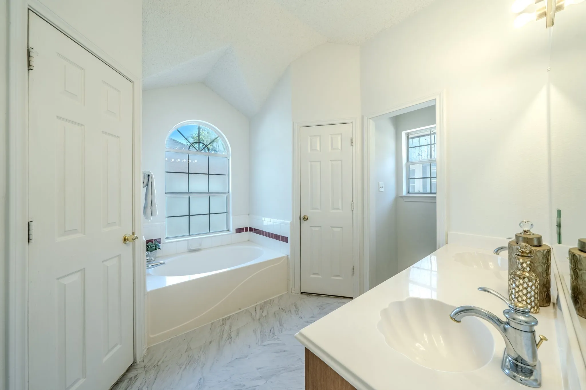 Beautifully renovated primary bathroom with dual-sinks, soaking tub, his and her closets, and gorgeous window!