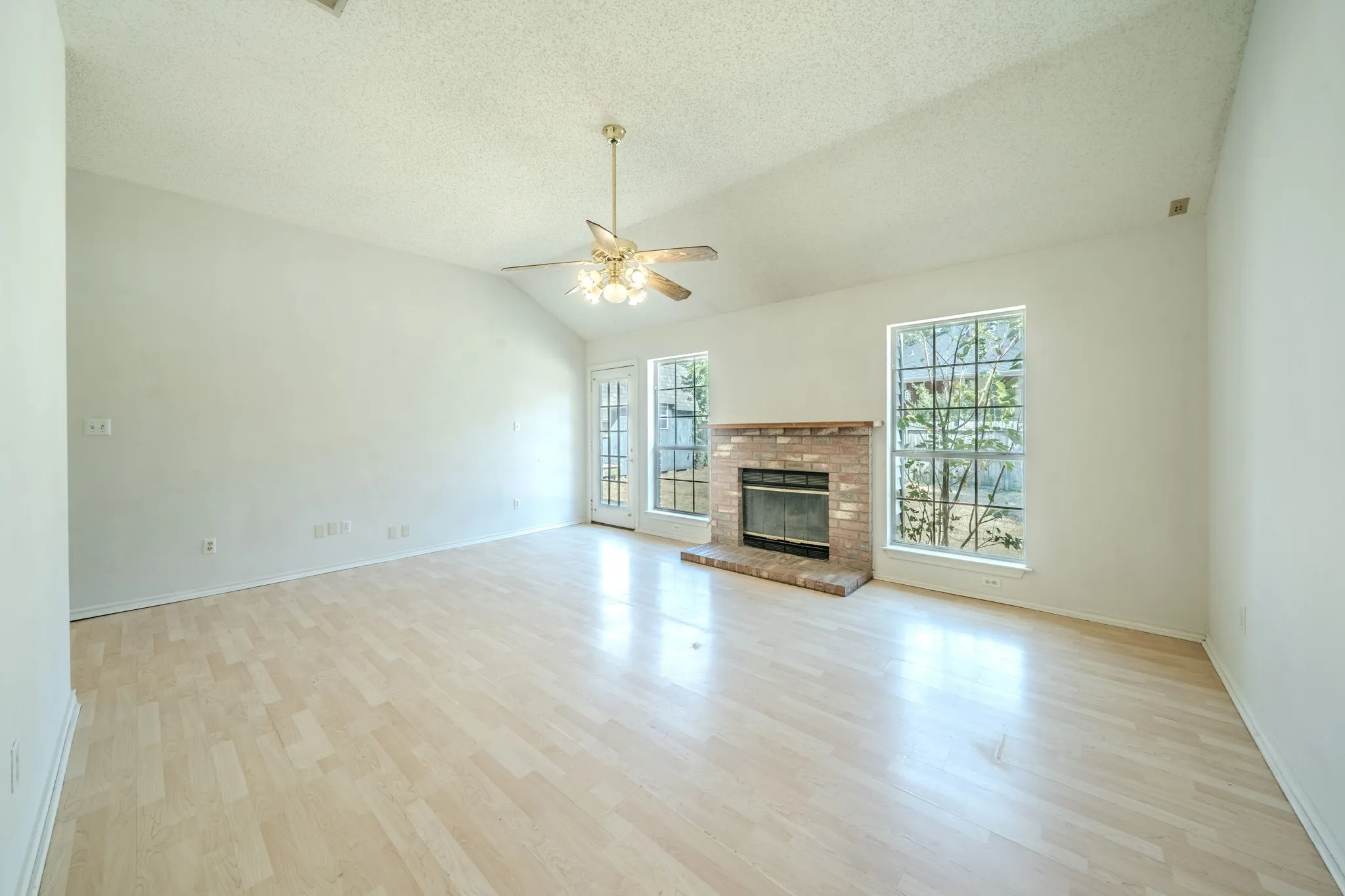 Spacious living room featuring laminate flooring, wood-burning fireplace, and tons of natural lighting.