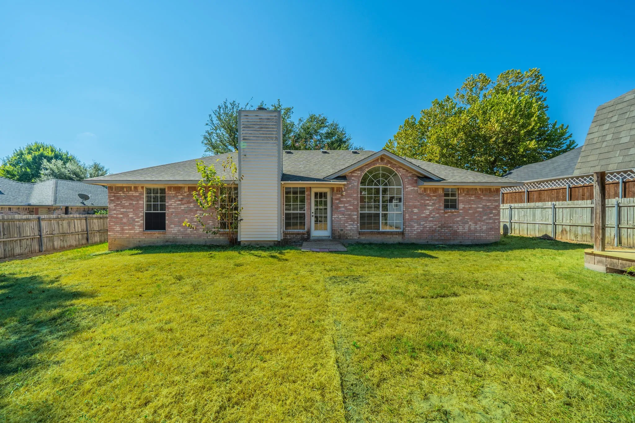 Another view of the expansive backyard featuring mature shade trees and a detached workshop/storage.