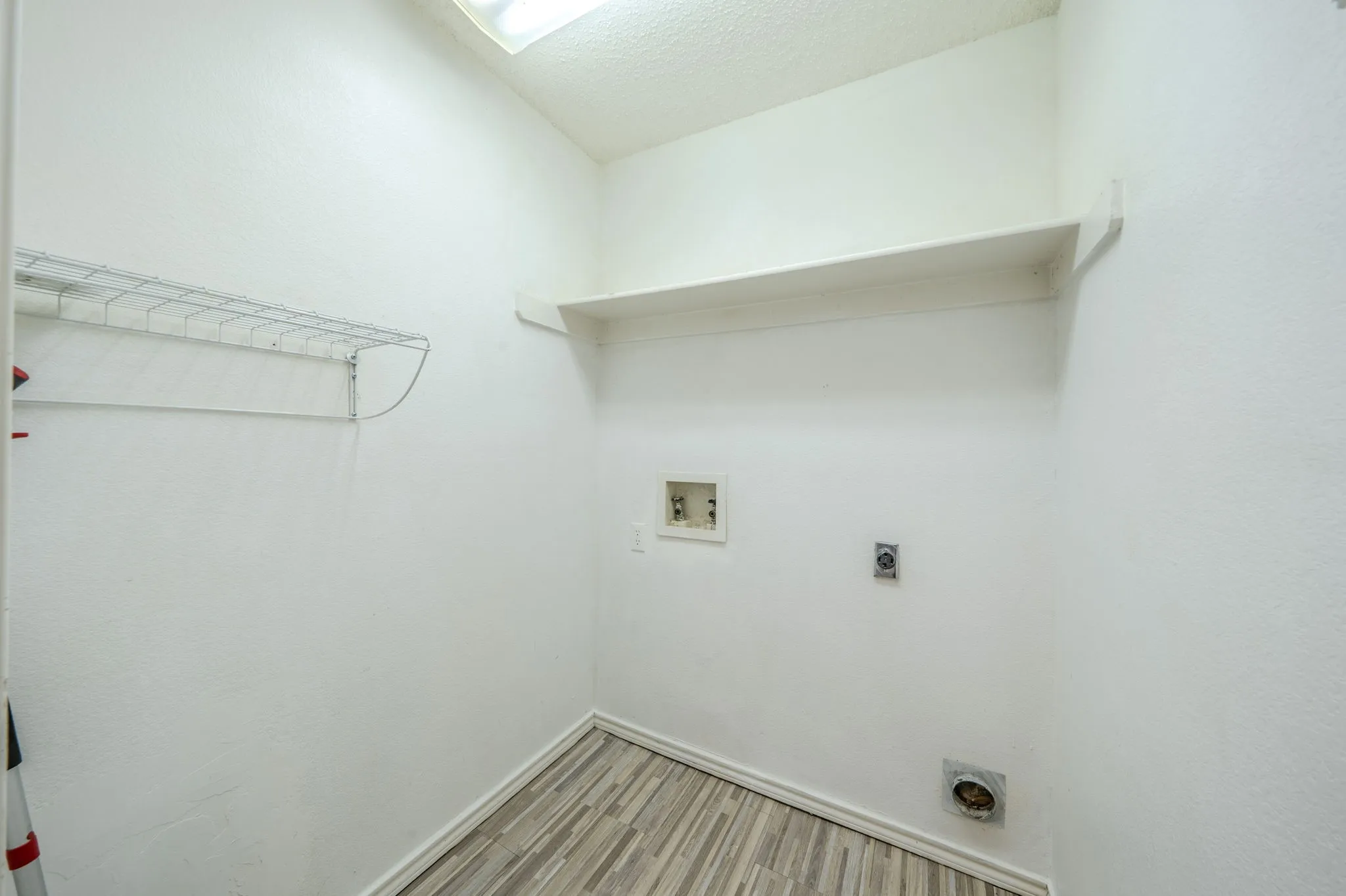 Laundry room with washer and dryer connections and shelving.