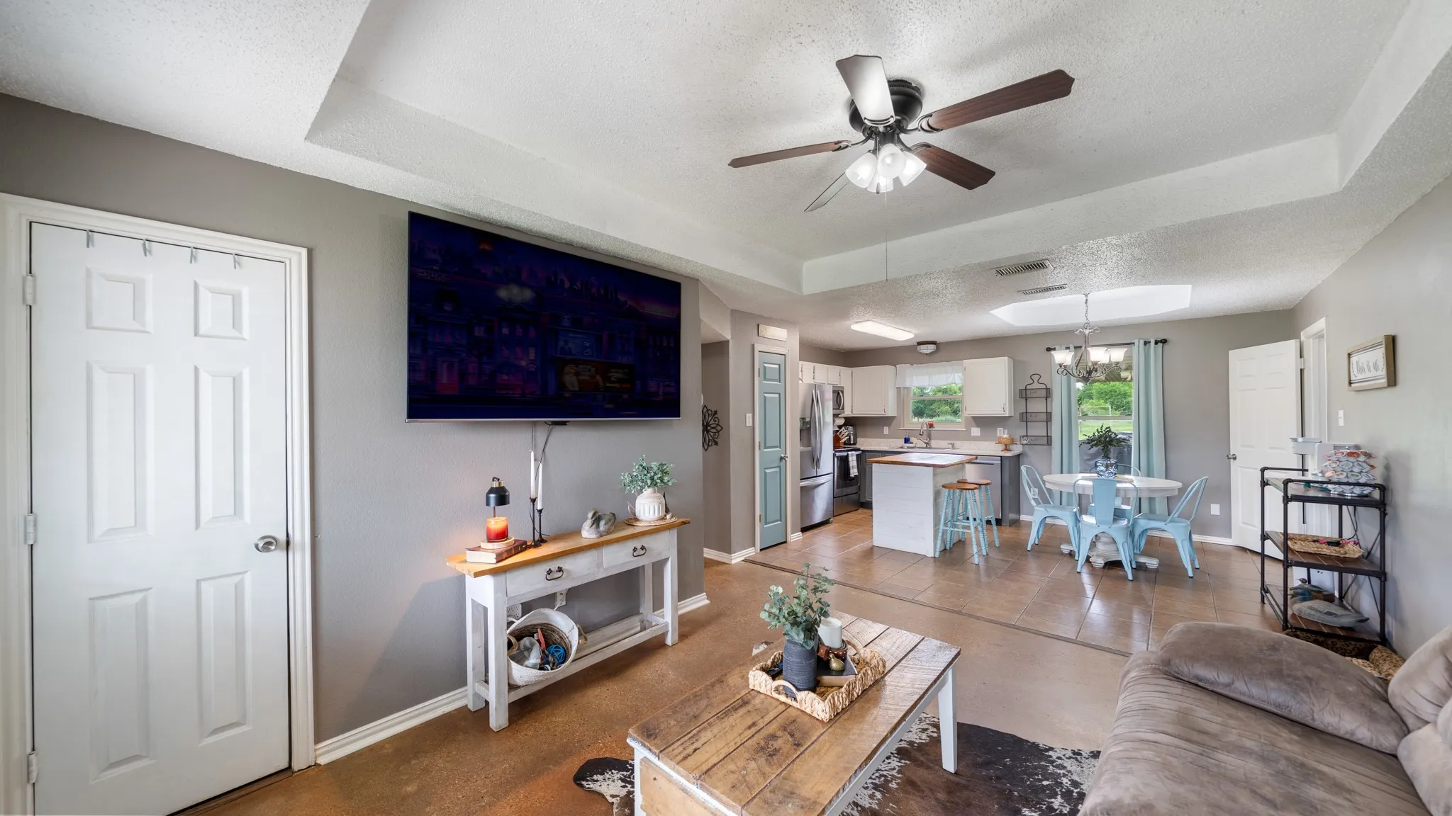 Open-concept living area featuring hardwood flooring, a coffered ceiling with recessed lighting and ceiling fan, and a wall-mounted flat-screen television