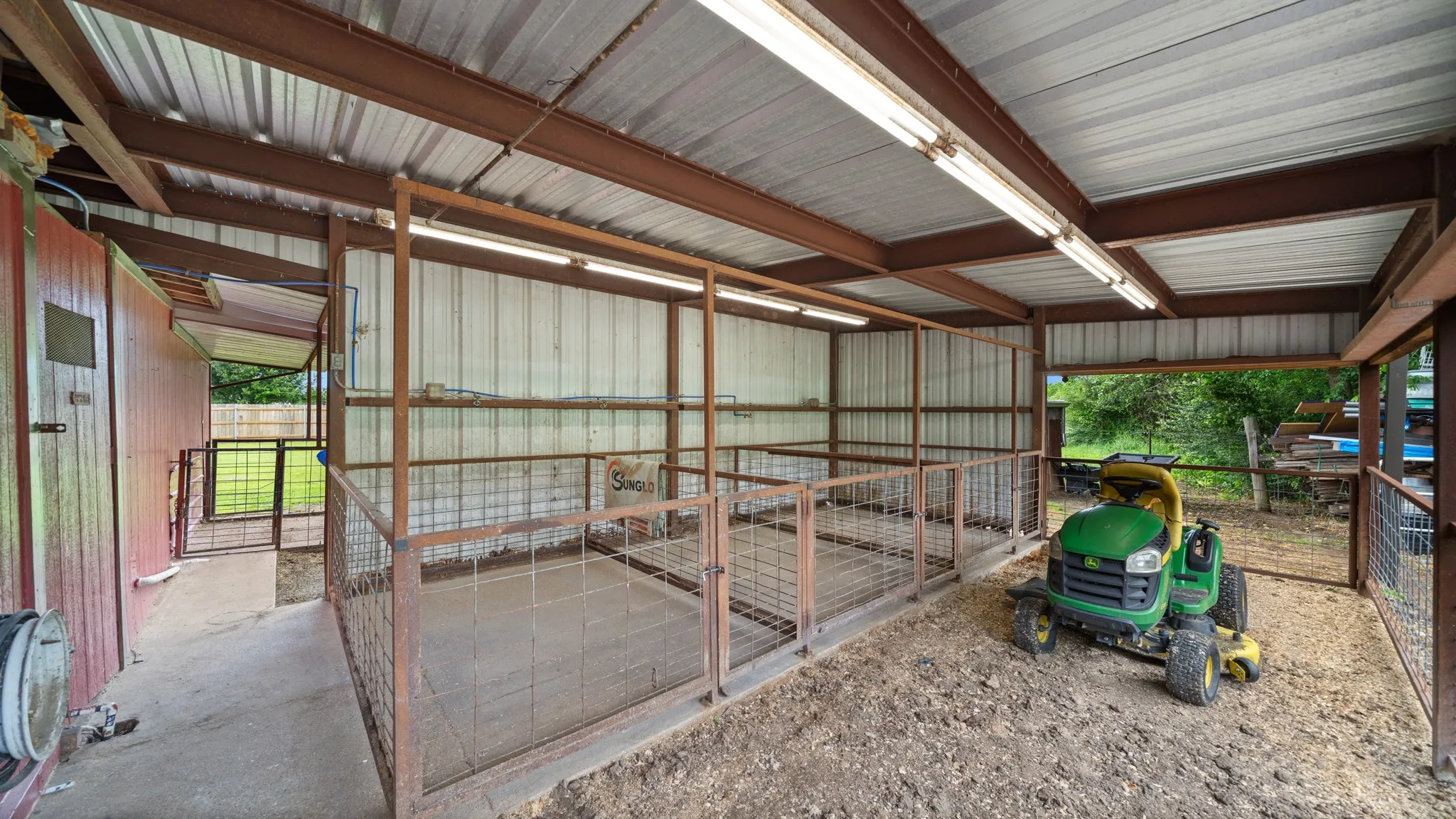 Spacious covered structure with metal-frame enclosures, concrete flooring, and corrugated metal roof