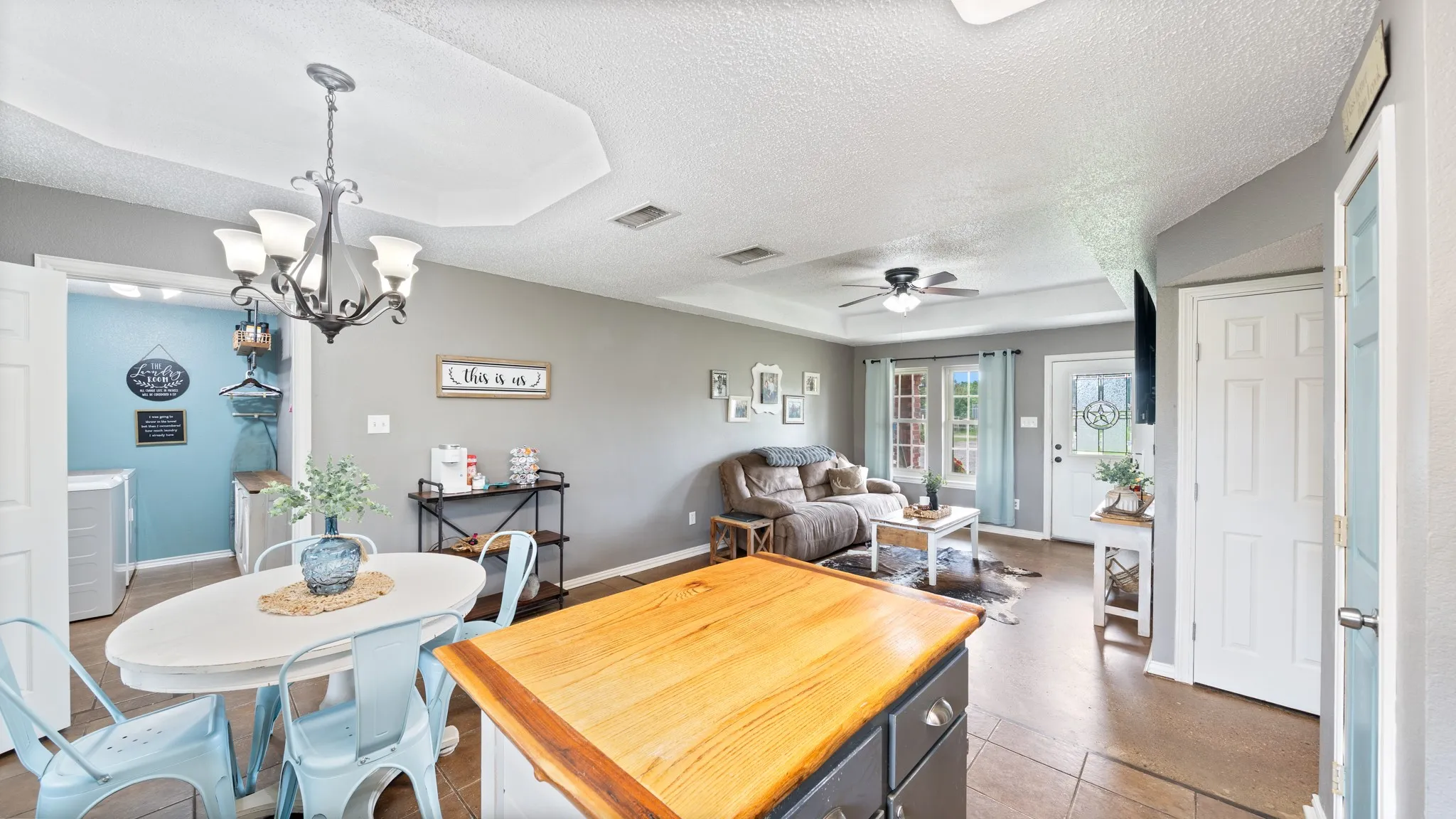 Open-concept kitchen and dining area featuring a large wood-finish island with prep space, ceramic tile flooring, recessed ceiling lighting, and a decorative chandelier