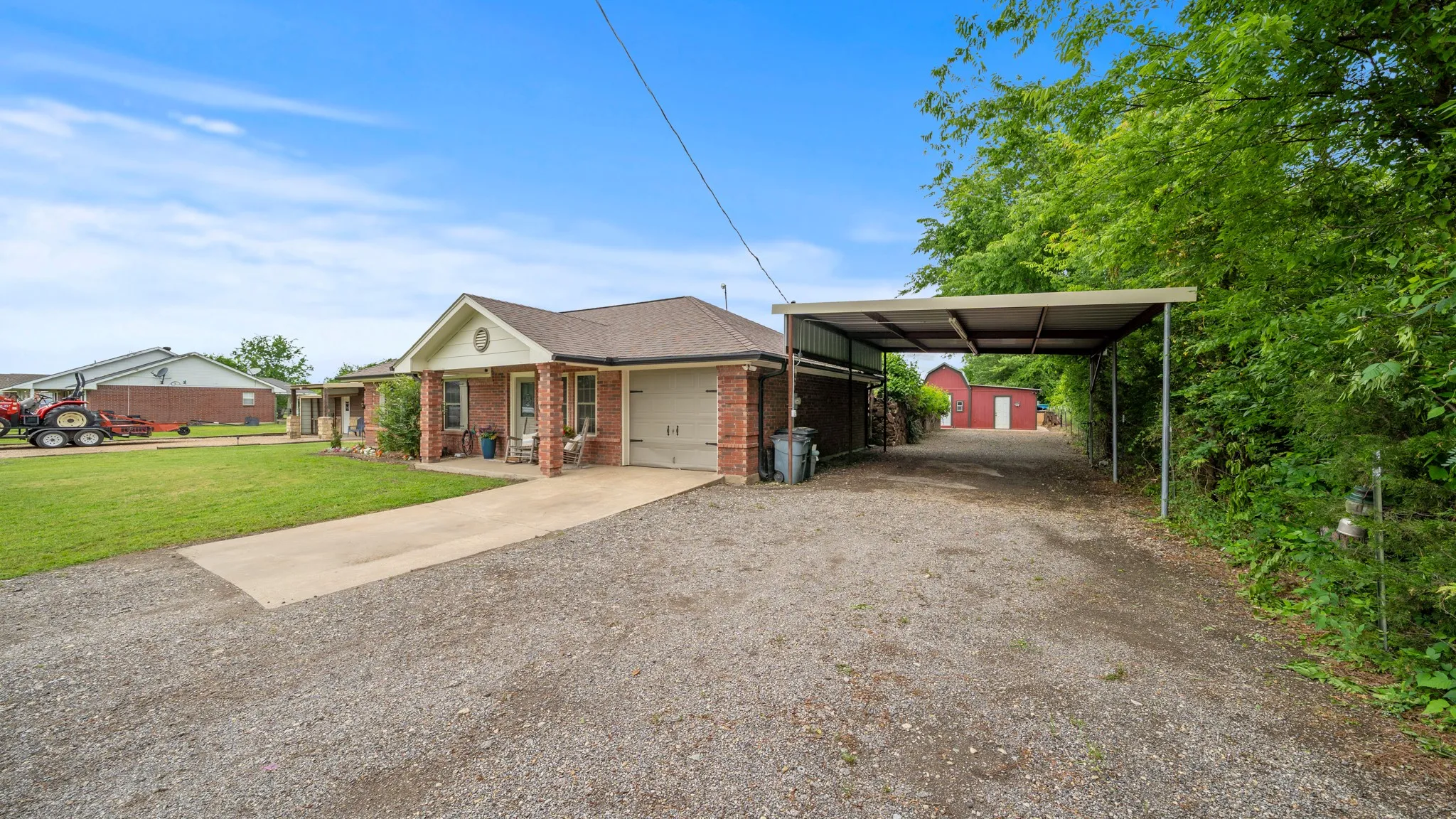 Brick residence with an attached garage and covered carport, situated on expansive grounds with mature landscaping and open lawn space