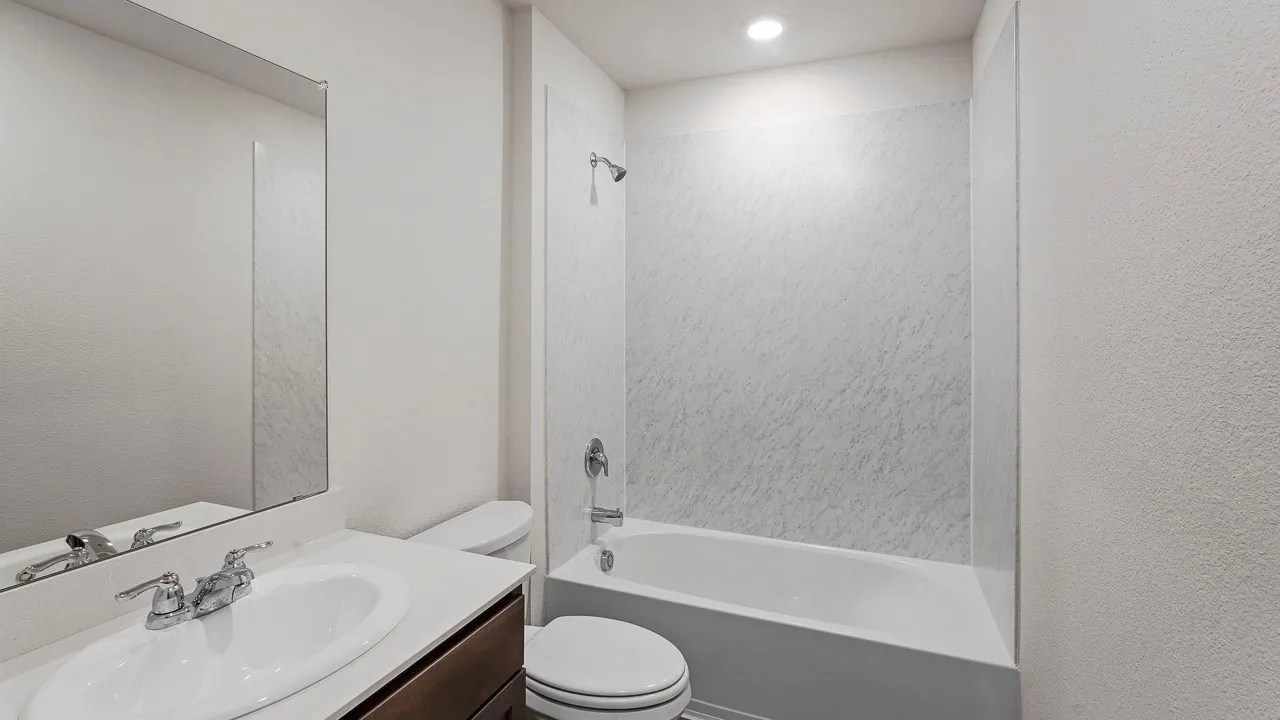 Contemporary bathroom featuring a floating vanity with rectangular vessel sink and chrome faucet, marble-look wall tile surround, recessed ceiling lighting, and an alcove bathtub with integrated shower and glass enclosure