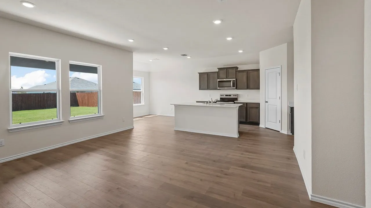Open-concept living space featuring wood-finish flooring throughout, recessed ceiling lighting, and abundant natural light from dual windows