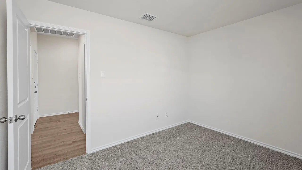 Neutral wall color, gray carpet, white trim, and wood-finish flooring in the adjacent area