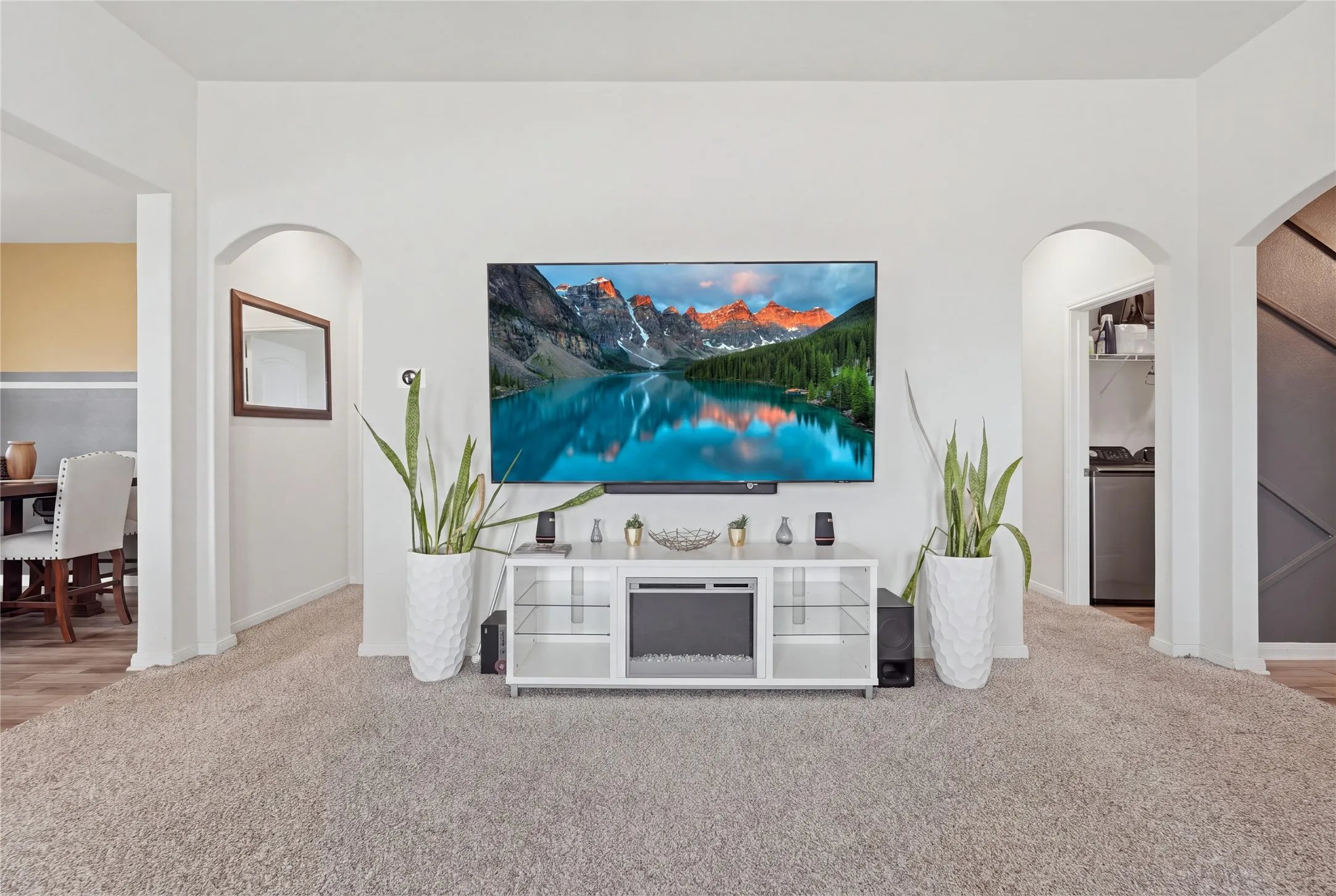 Spacious family room showcasing neutral carpeting, recessed ceiling lighting, and a white media console with integrated storage