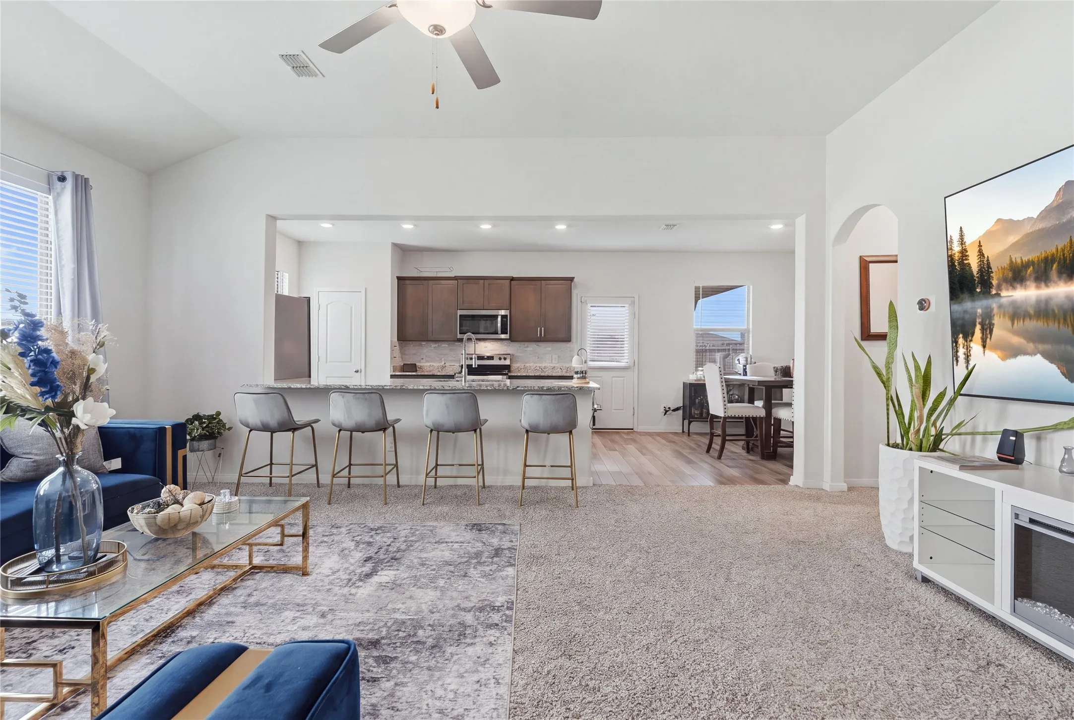 Open-concept living and dining area featuring neutral carpeting, recessed ceiling lighting, and a ceiling fan