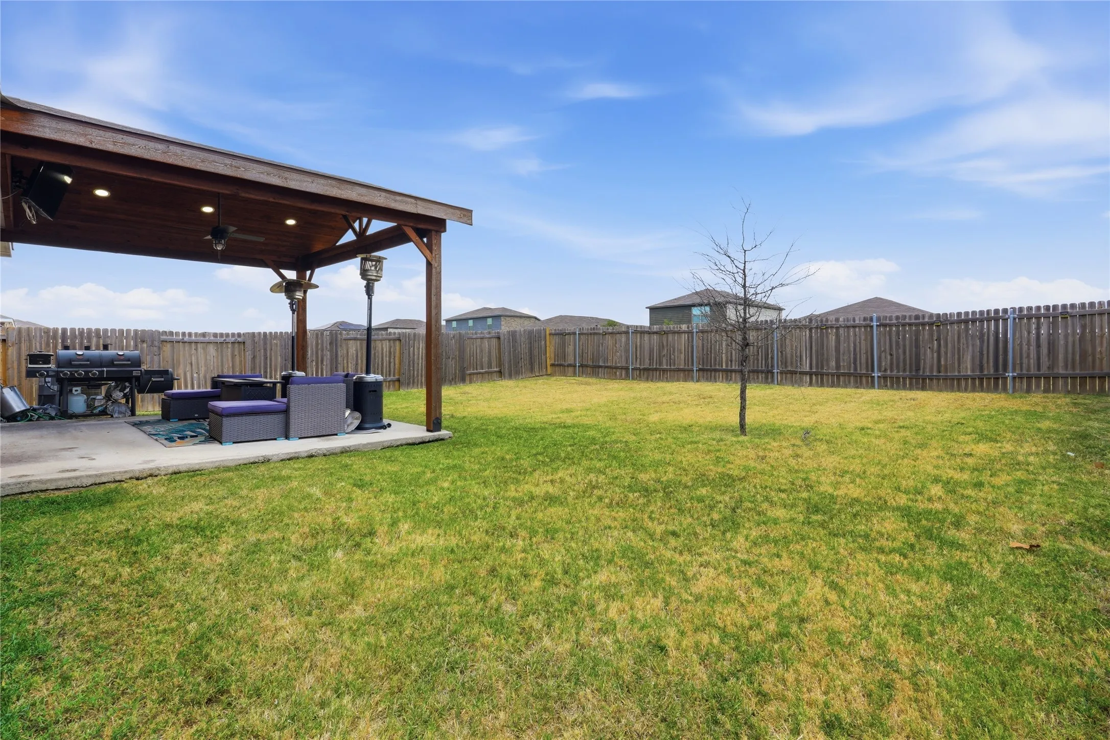 Expansive backyard with mature landscaping and lush green lawn, anchored by a sturdy wood-beam pergola with integrated lighting