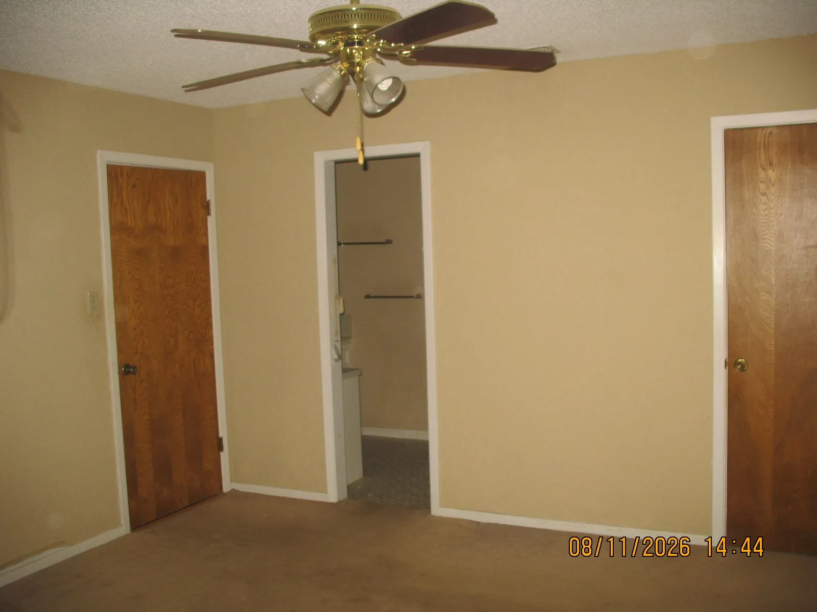 Carpeted flooring, neutral wall paint, wood-finish doors, and a ceiling fan with integrated lighting