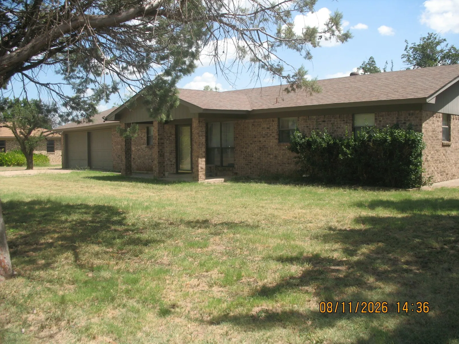 Brick exterior, attached two-car garage, established landscaping, and a pitched roof