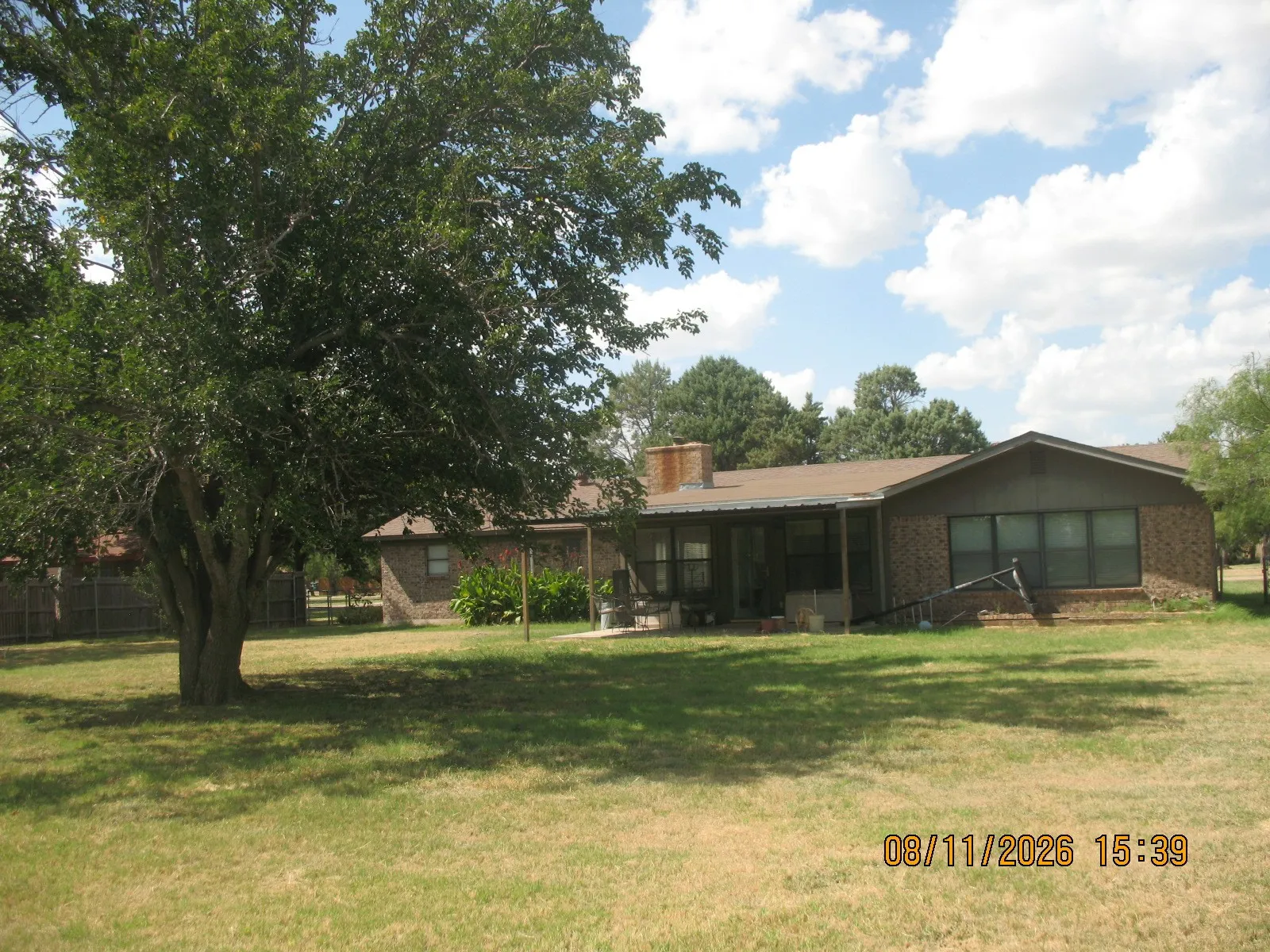 Brick exterior with a covered patio, multiple windows, and a prominent chimney