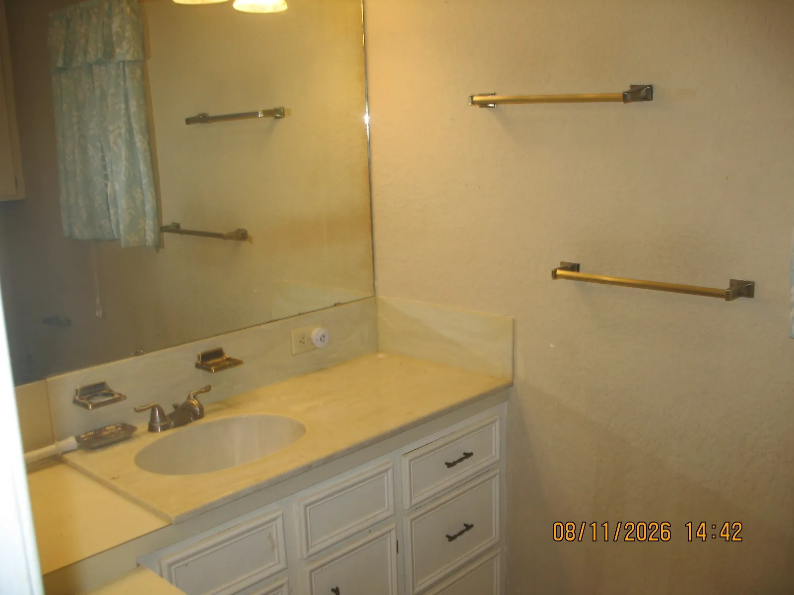 Vanity with integrated sink, expansive mirror, and brass-tone fixtures
