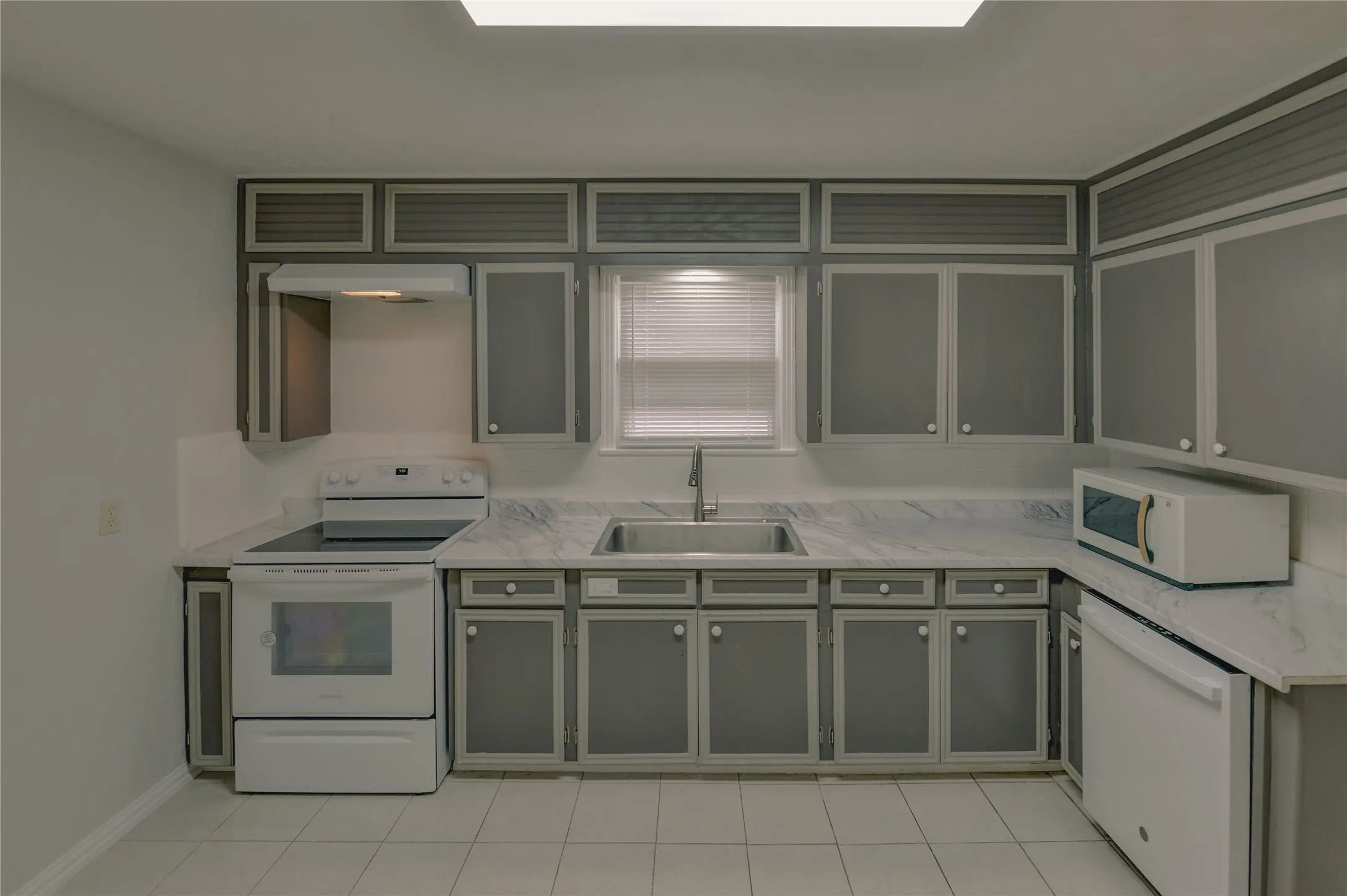 Kitchen has a dishwasher, microwave, exhaust fan and stove with white/cream ceramic floors