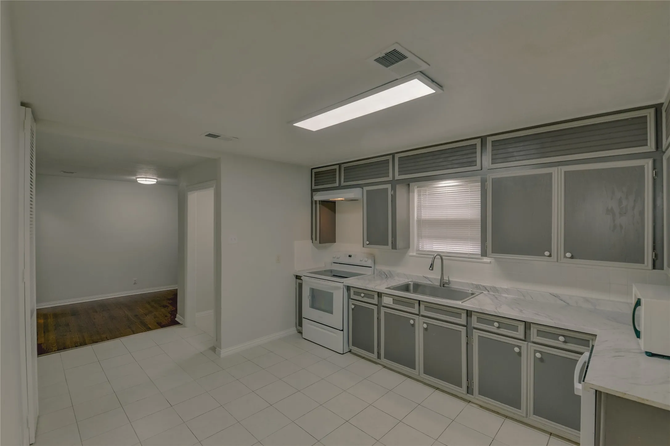 Kitchen with lots of cabinets, farmers sink, exhaust fan, and window over the sink