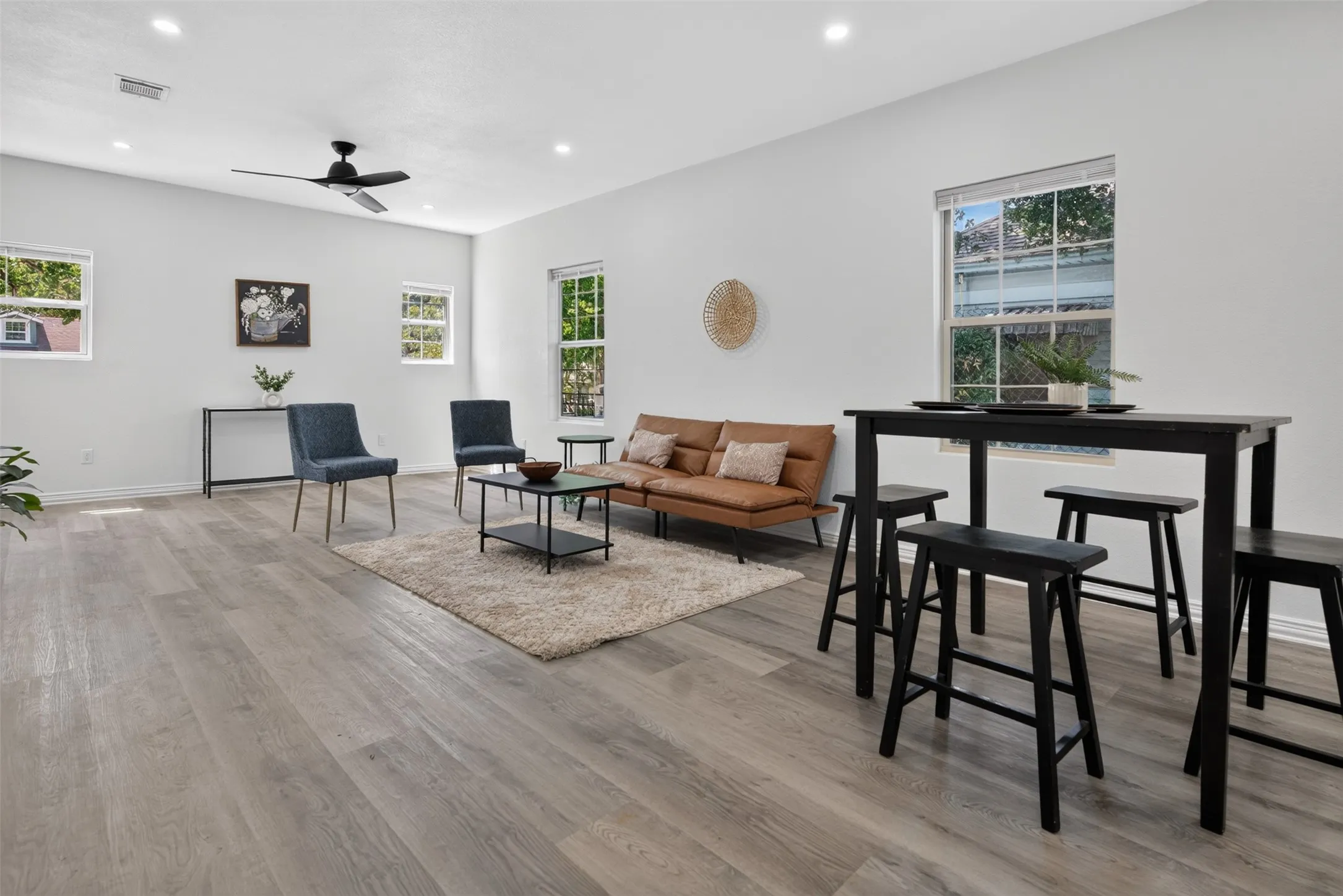 Open-concept living space featuring wide-plank wood-finish flooring throughout, recessed ceiling lighting, and a ceiling fan