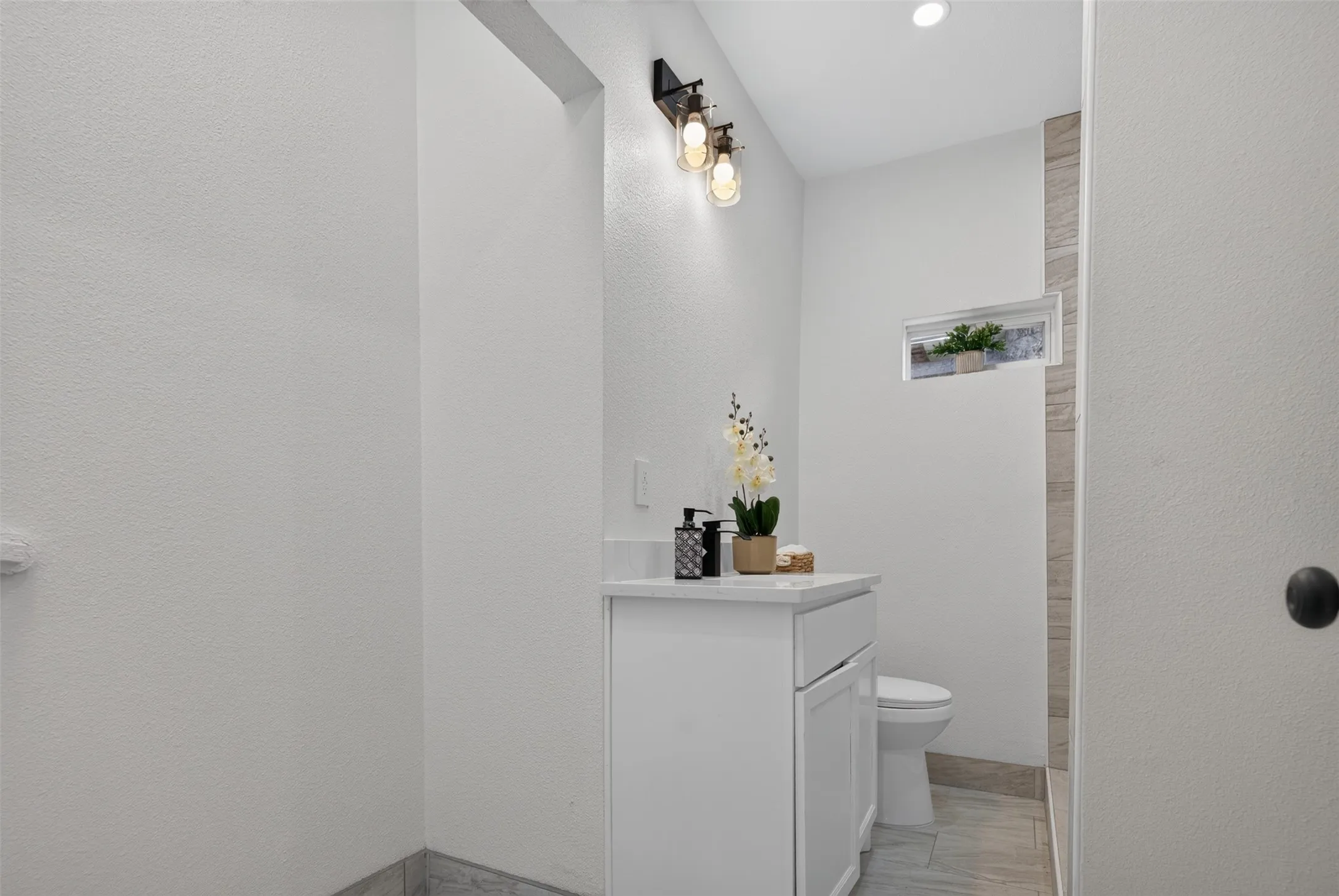 Modern powder room featuring a streamlined white vanity with integrated storage, quartz countertop, and chrome fixtures