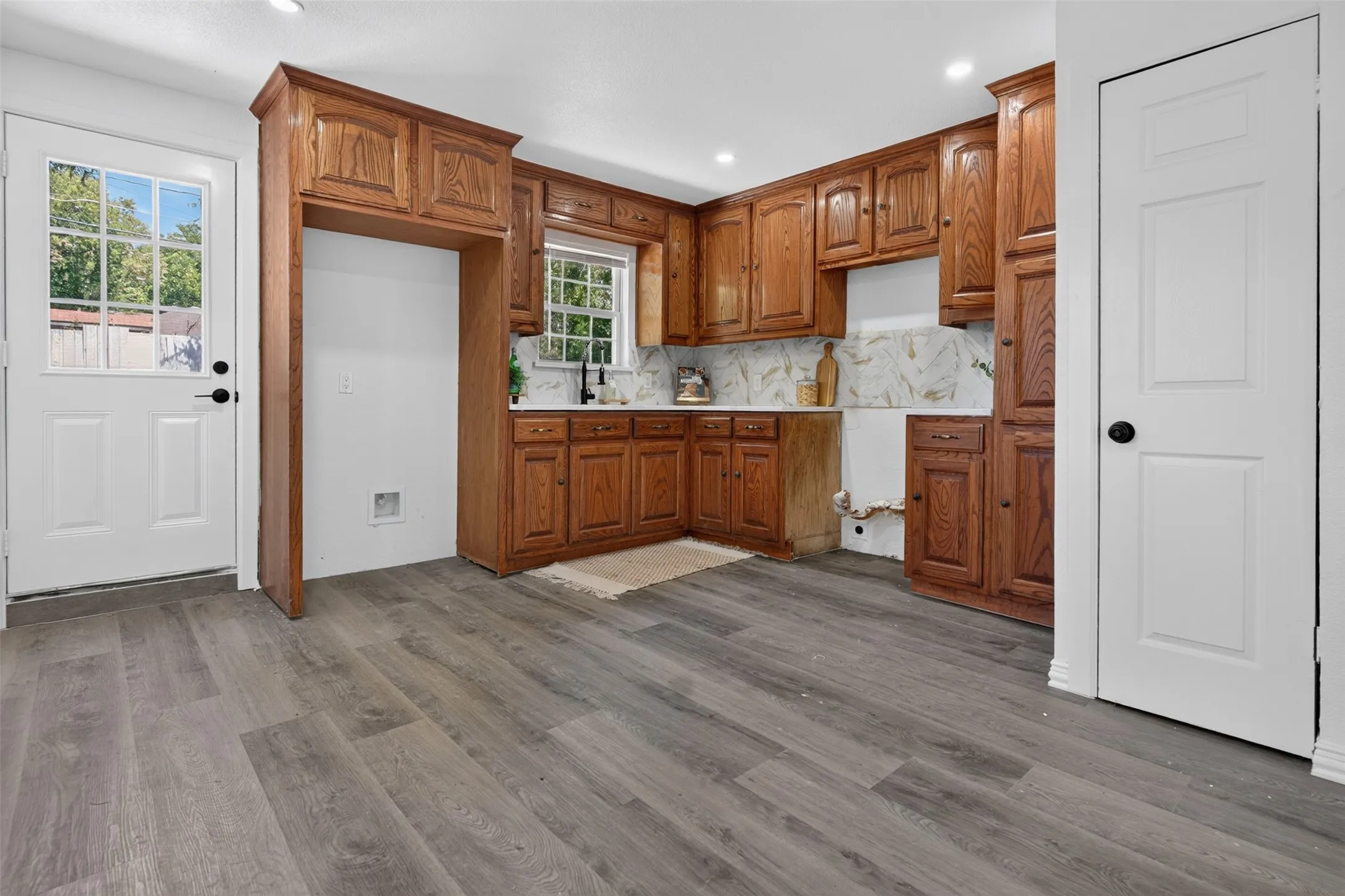 Spacious kitchen featuring rich wood cabinetry with raised-panel doors, marble subway tile backsplash, and stainless steel appliances